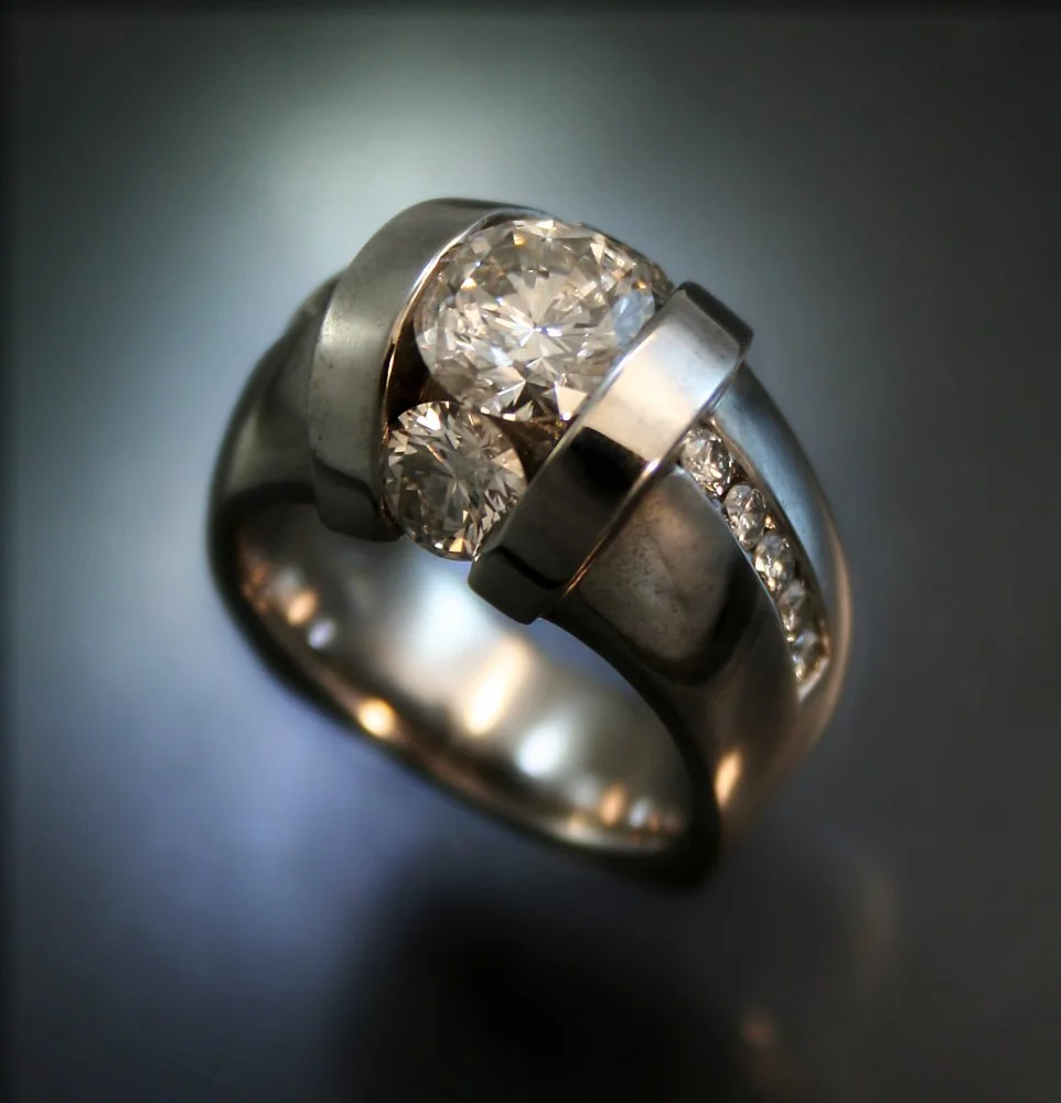 A silver ring with large central diamond and smaller diamonds along the band.