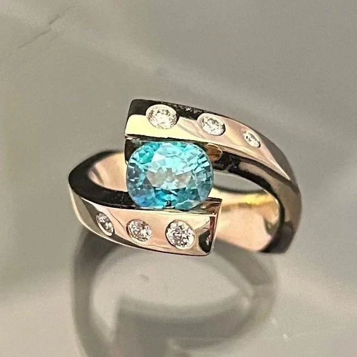 A ring featuring a large blue gemstone in the center and smaller clear gemstones embedded in the band.