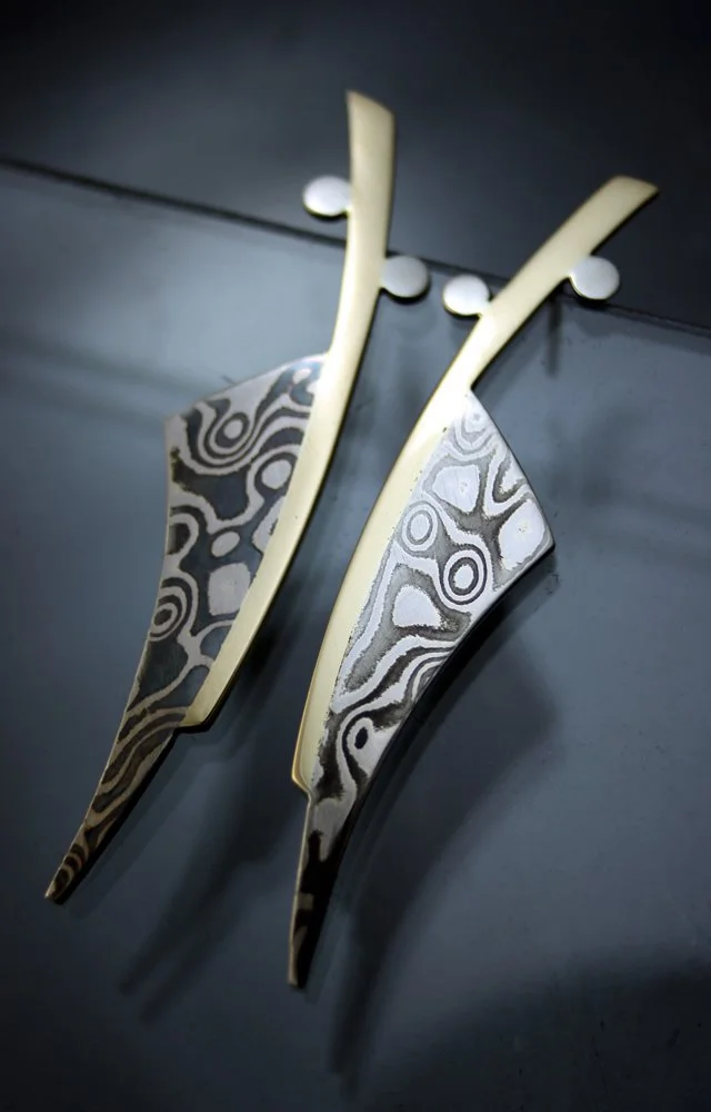 Wall-mounted abstract art sculpture resembling stylized arrows or feathers with intricate black, white, and gray patterns and cream-colored accents.