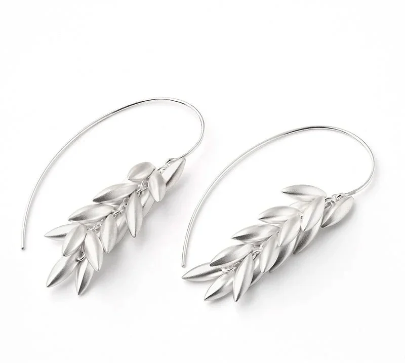 Silver leaf-shaped earrings with long hooks on a white background.