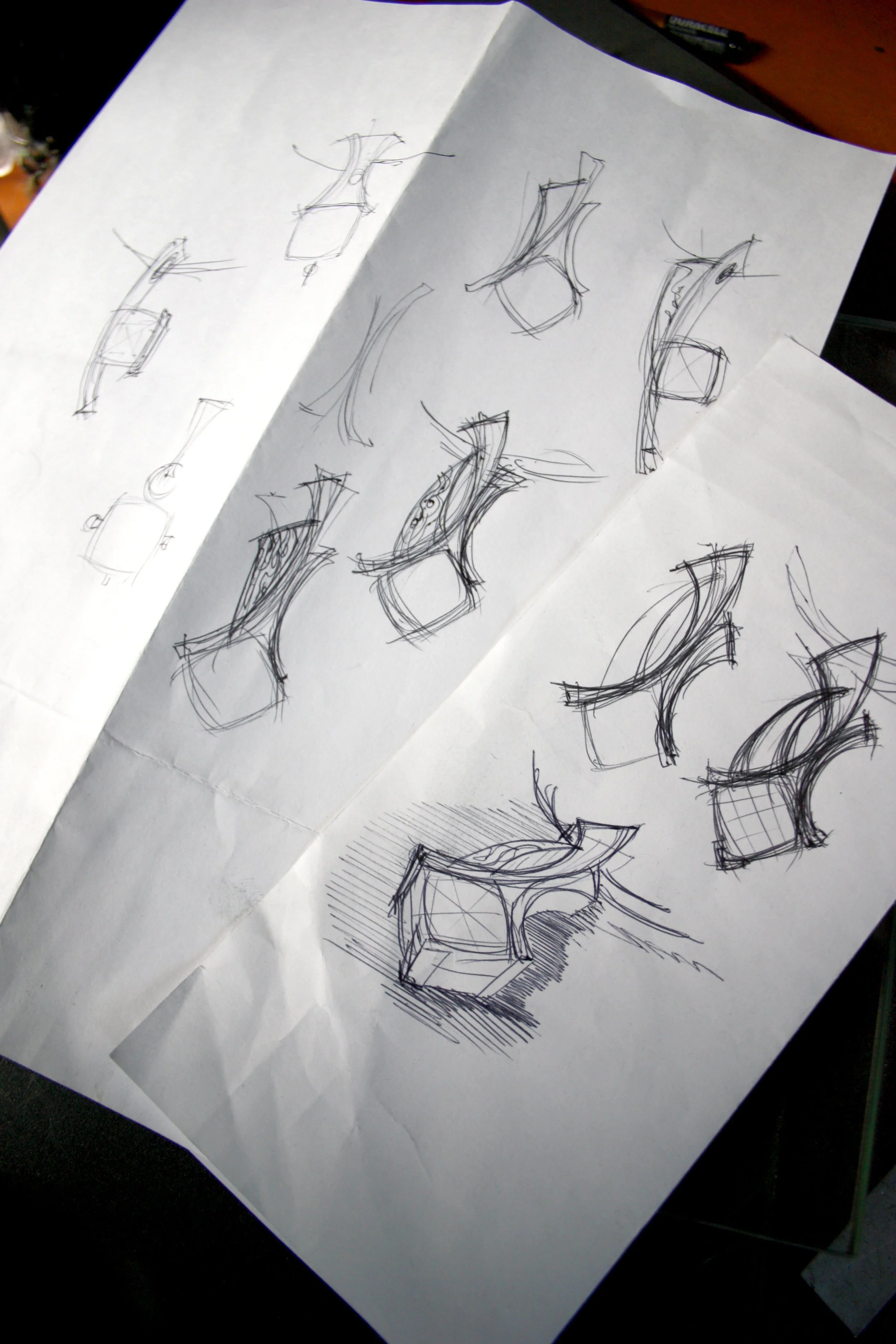 Sketch drawings of various chair designs and perspectives on white paper.