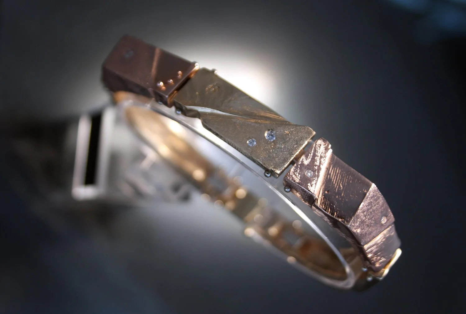 Close-up of a metallic bracelet with rectangular links on a dark background.