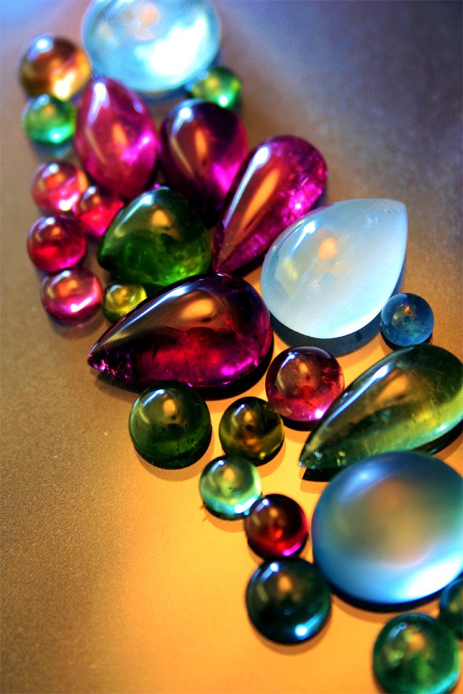 Colorful glass marbles of various sizes and shapes scattered on a reflective surface.