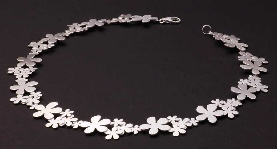 Silver flower-shaped necklace on black background.
