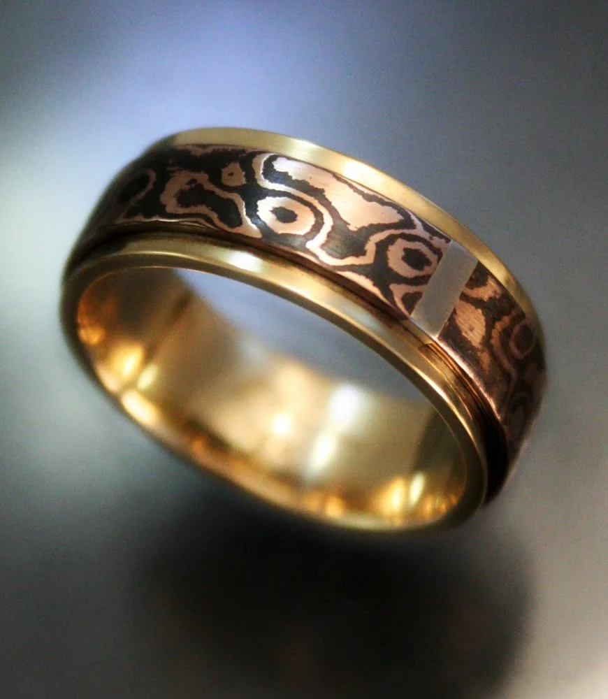 Close-up of a gold ring with black patterned inlay design.