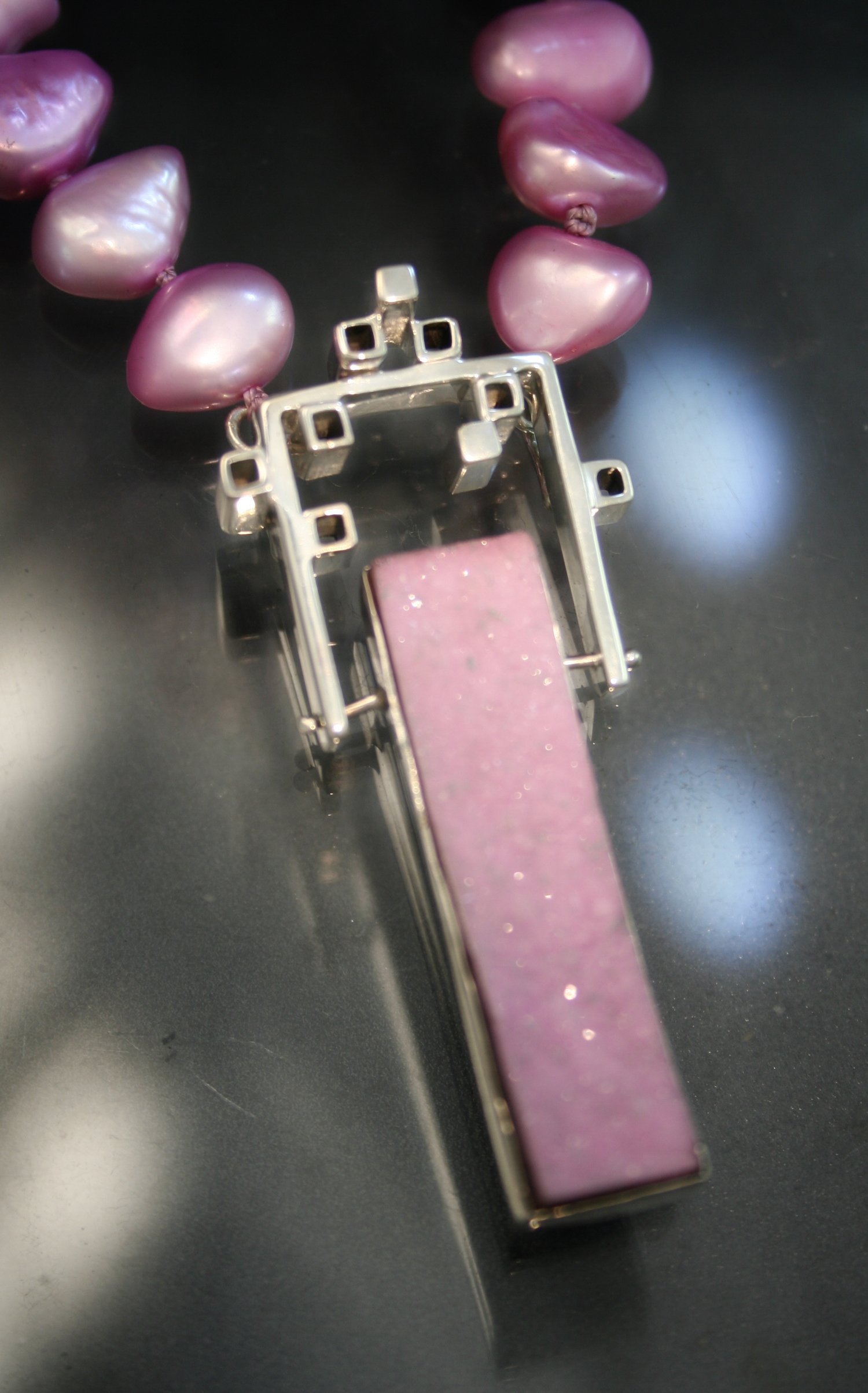 A rubber stamp with purple ink on a black surface, surrounded by a purple pearl necklace.