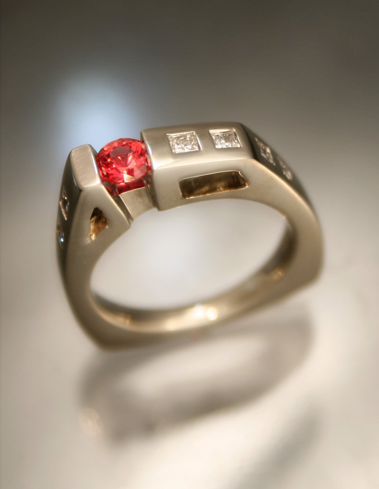 Close-up of a silver ring with a red gemstone and several small diamonds embedded in the band.