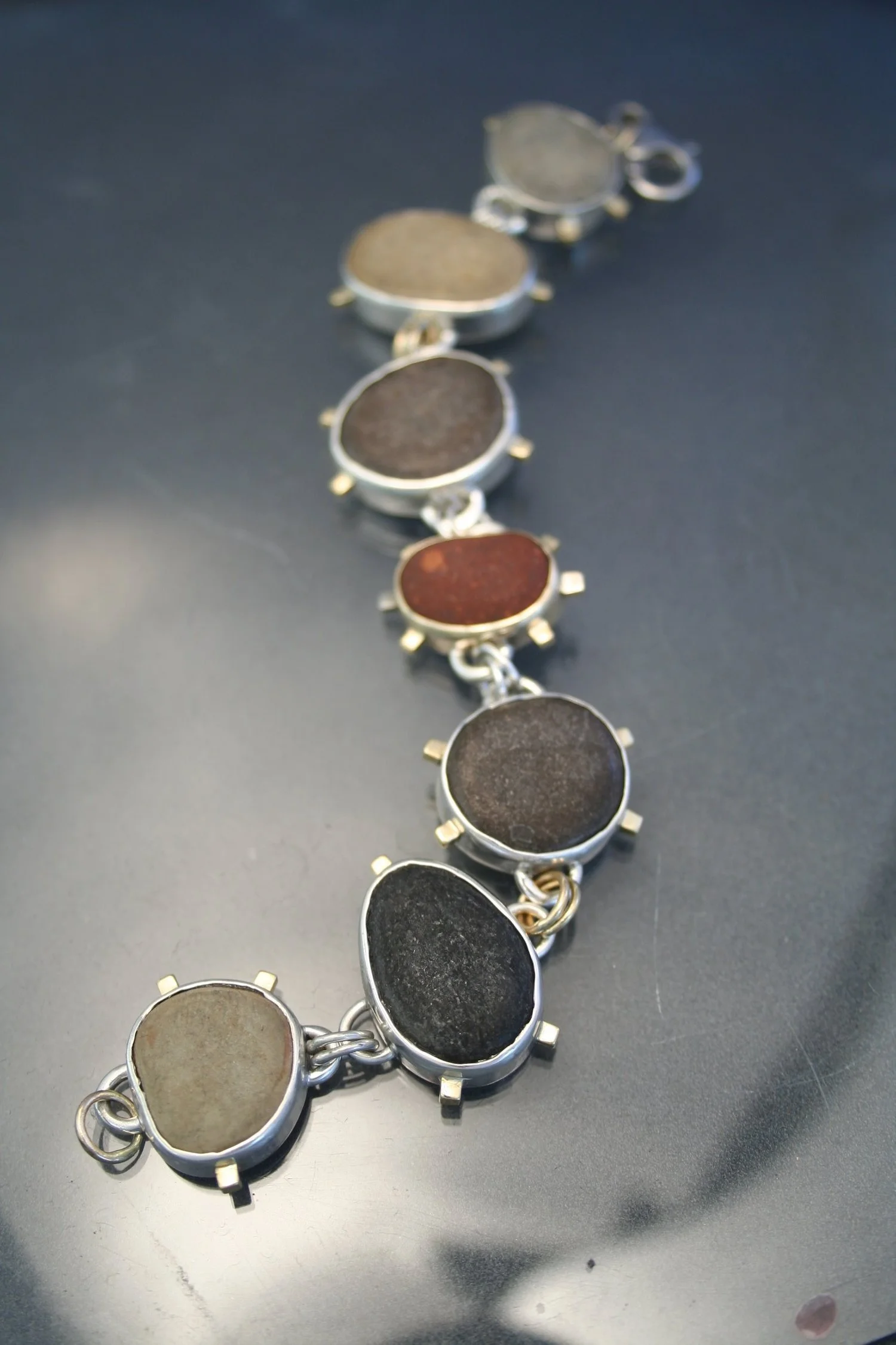 Close-up photo of a multi-colored gemstone bracelet with oval stones set in silver.