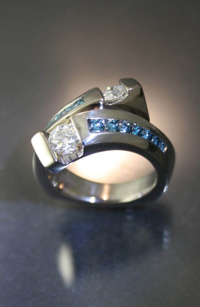 A silver ring with multiple diamonds and blue gemstones set into the band.