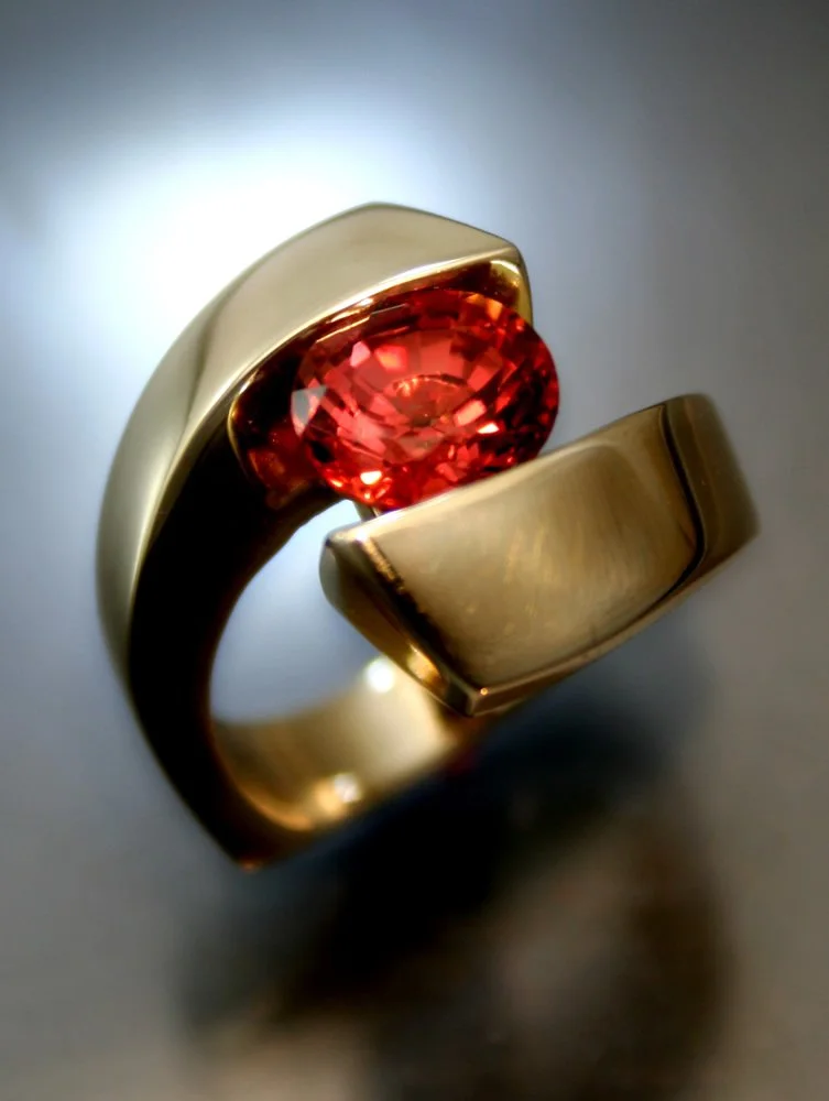 Gold ring with a large, faceted red gemstone.