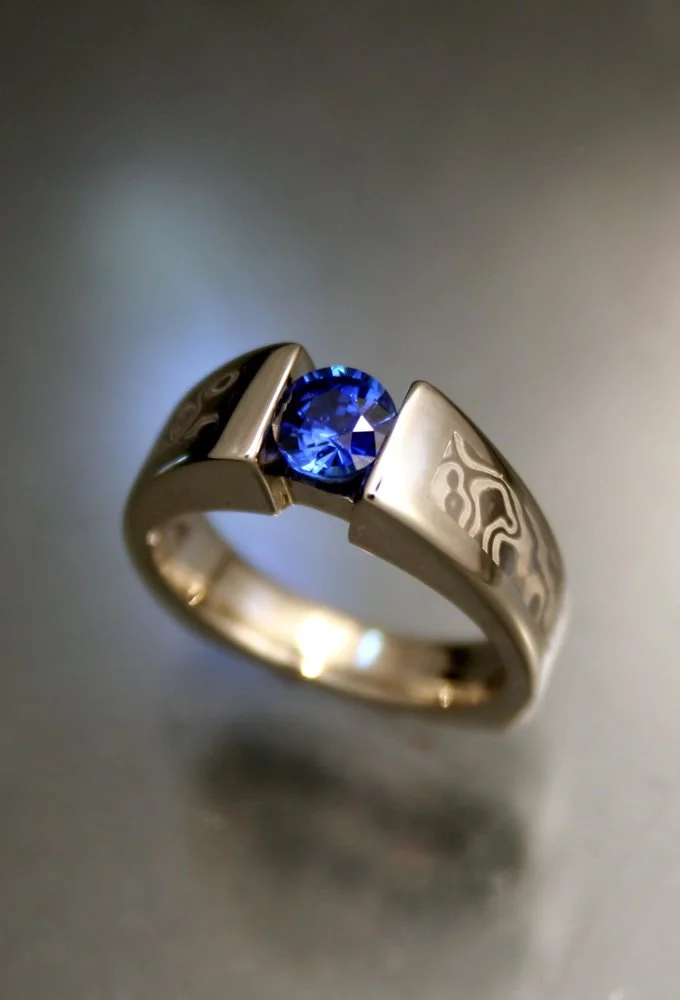 A silver ring with a blue gemstone in a modern, geometric setting.