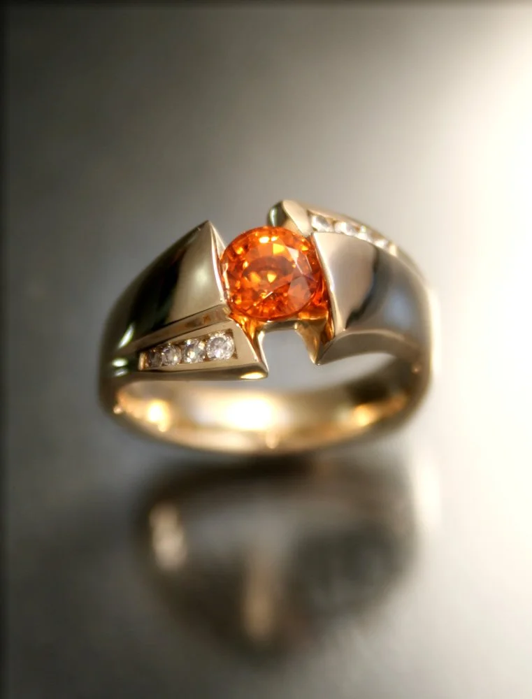 A silver ring with an orange gemstone and small diamonds.