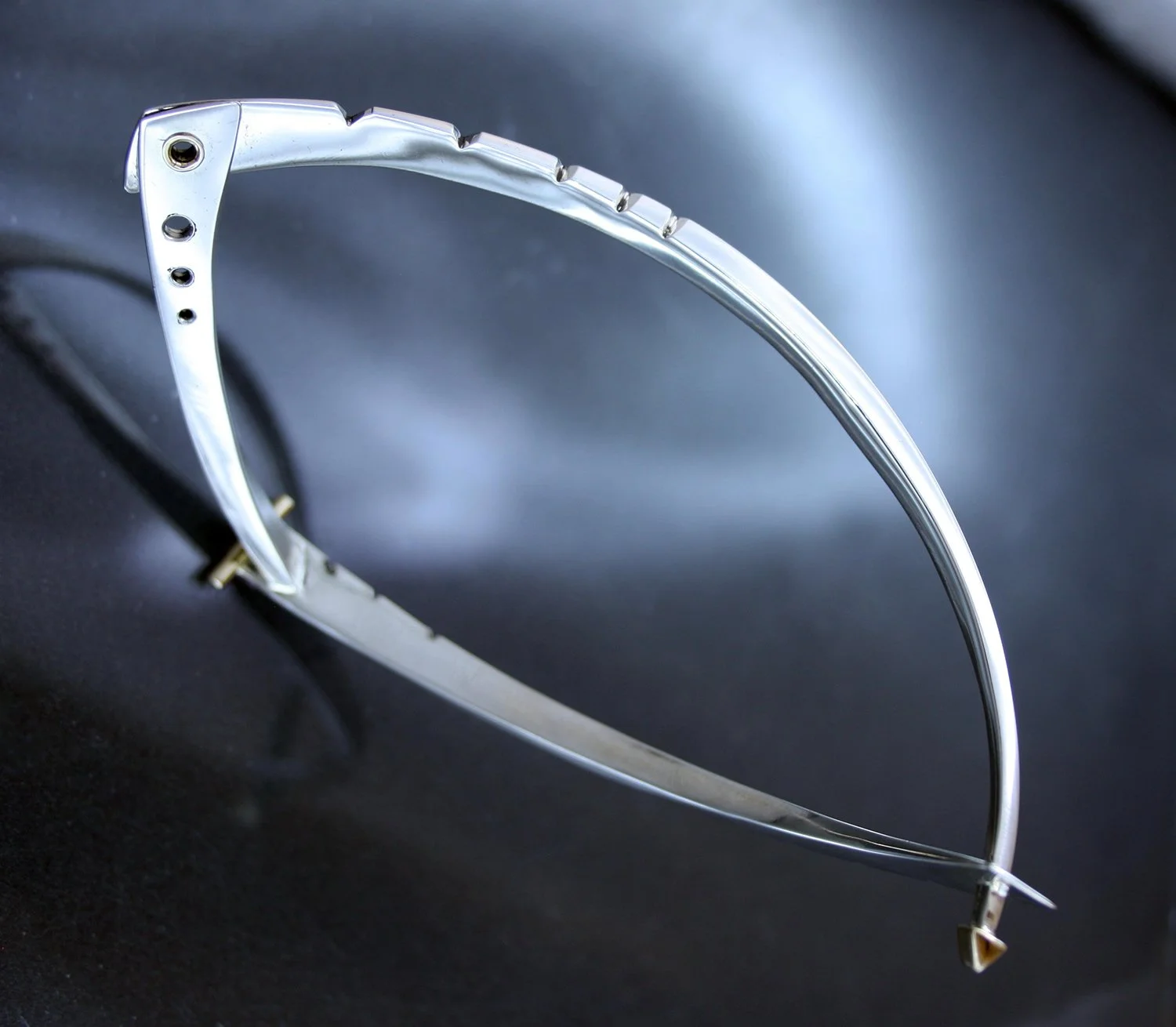 Close-up of a metallic headband with decorative details on a dark surface.