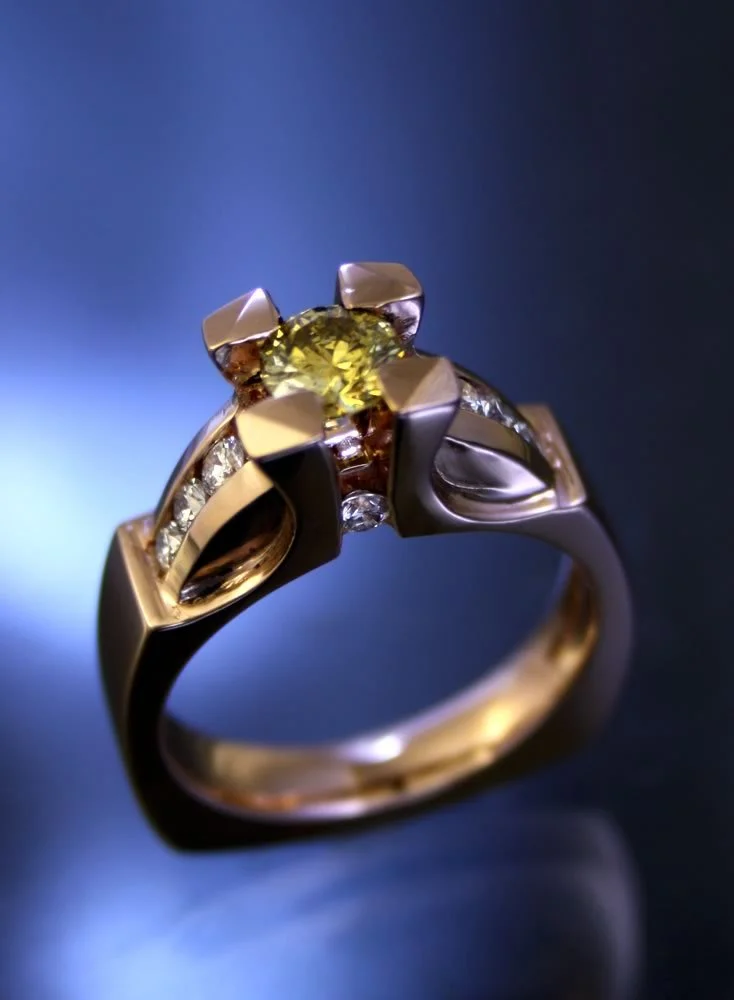 A gold and silver ring featuring a large yellow gemstone and smaller clear stones set into the band.