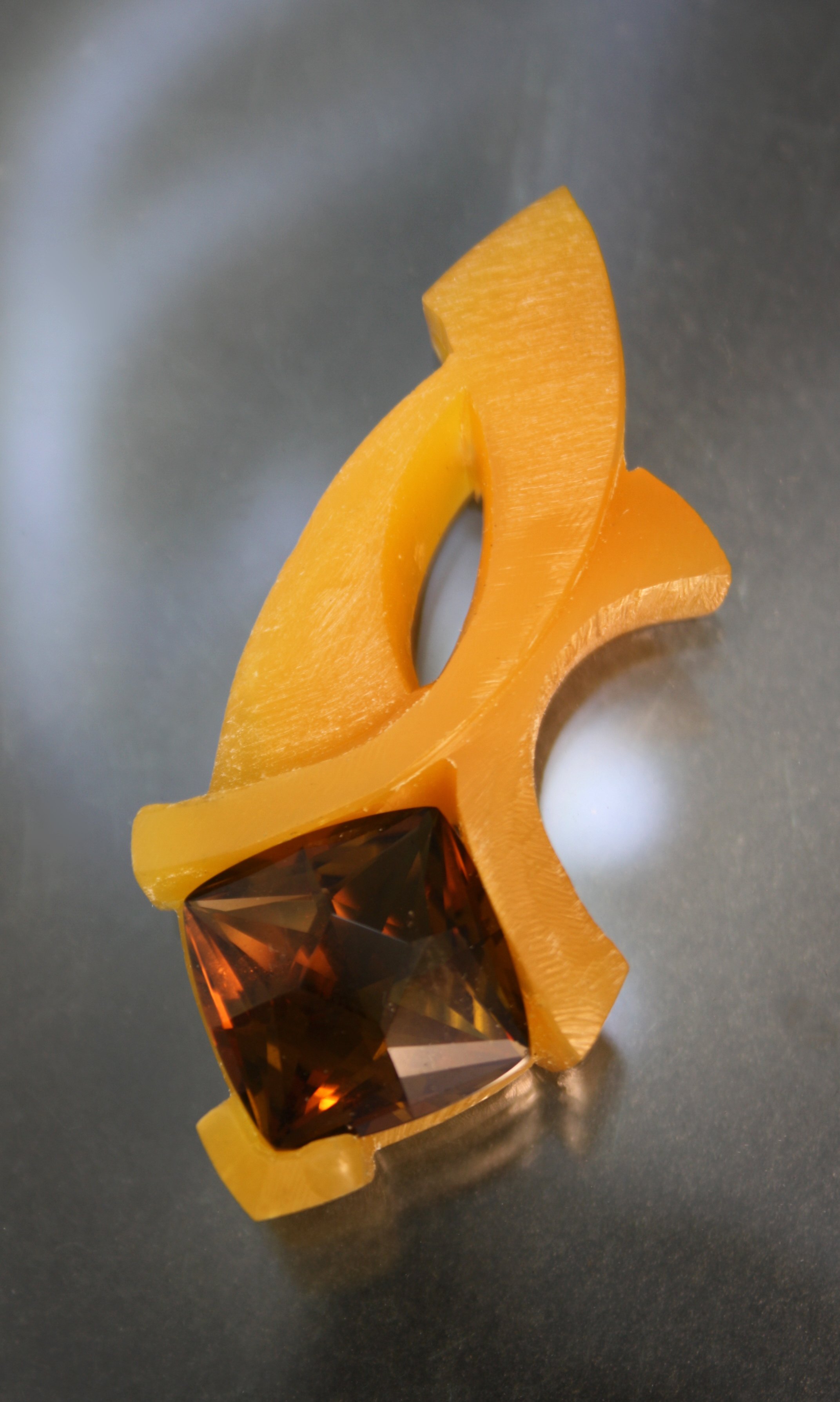 A chunky, yellow, plastic ring with a large, square, faceted amber-colored gemstone set at the front.