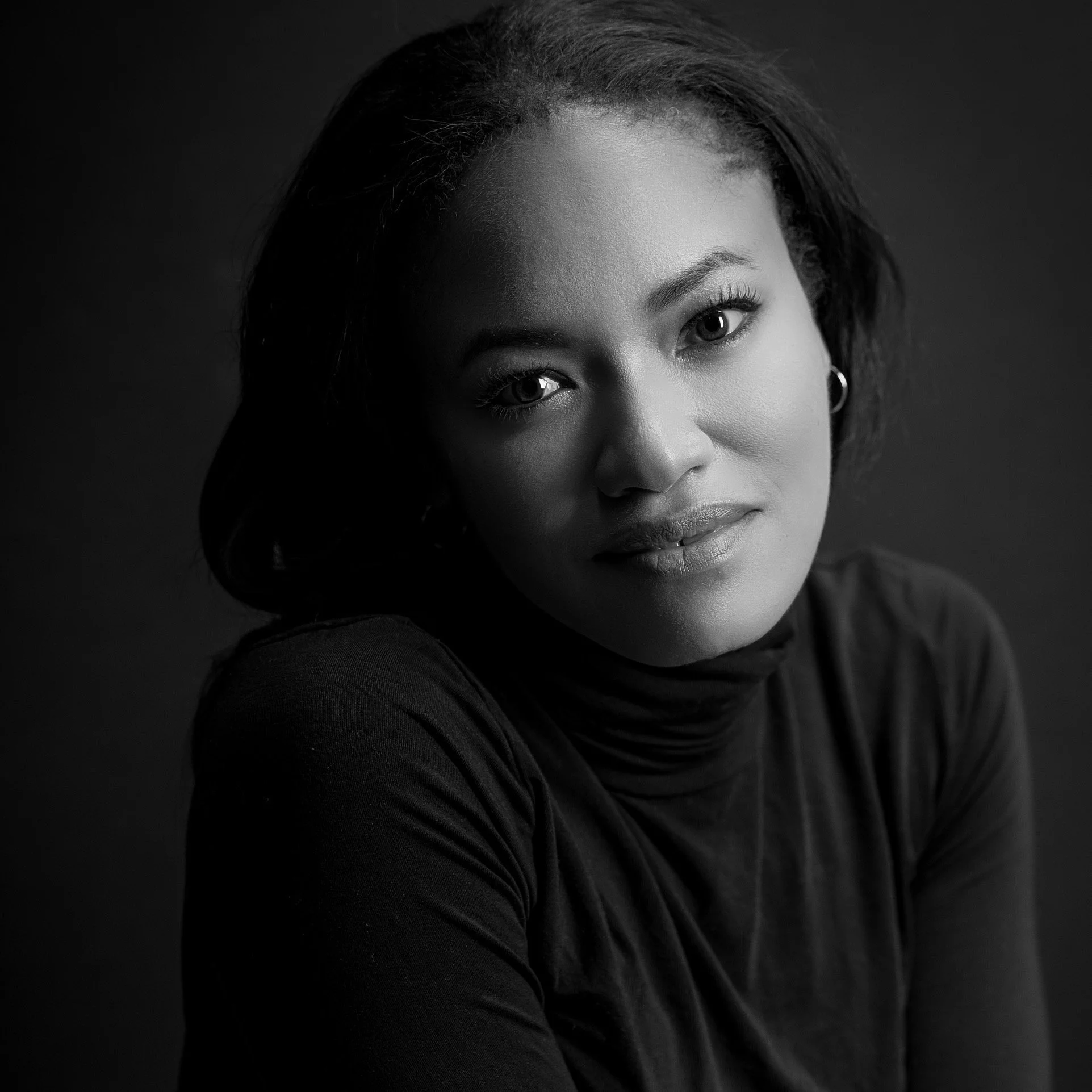 Black and white portrait of a woman with shoulder-length hair, wearing a turtleneck, looking directly at the camera with a slight smile.