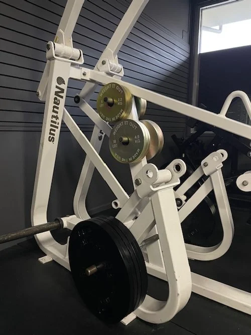 Fitness equipment with weight plates and a barbell in a gym setting.