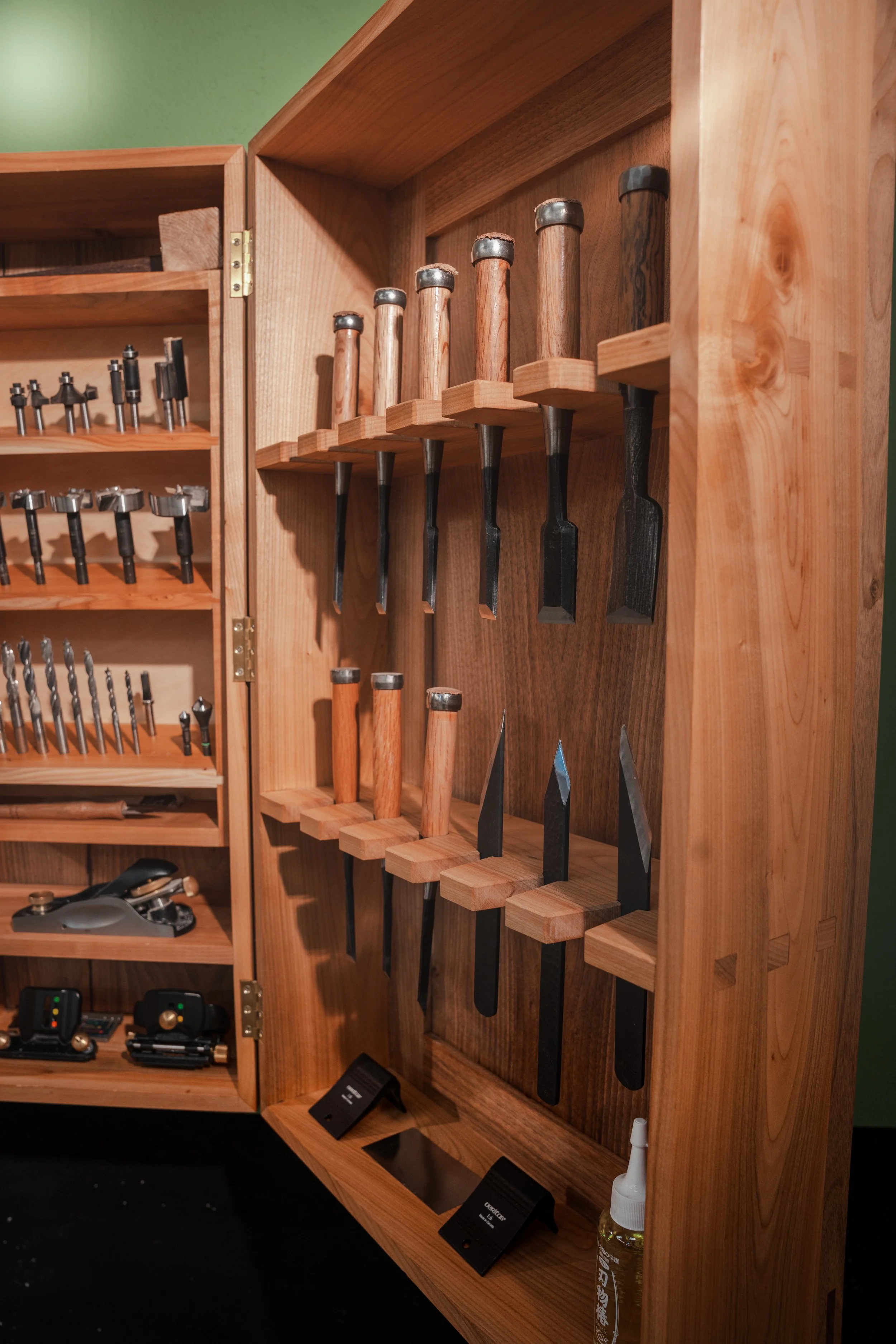 Holzschrank mit Handwerkzeugen, darunter Meißel und Schraubenzieher, in einer Werkstatt.