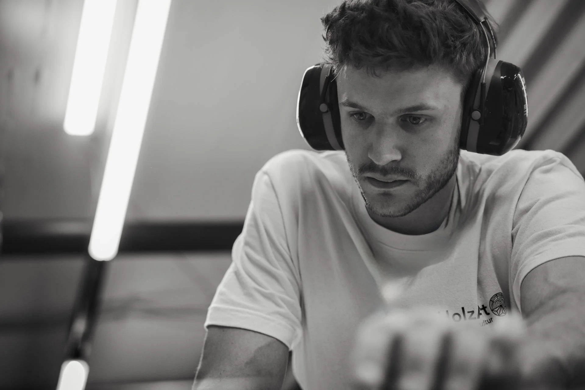 Schwarz-weiß-Foto eines jungen Mannes mit Headset, der konzentriert an einer Aufgabe arbeitet.