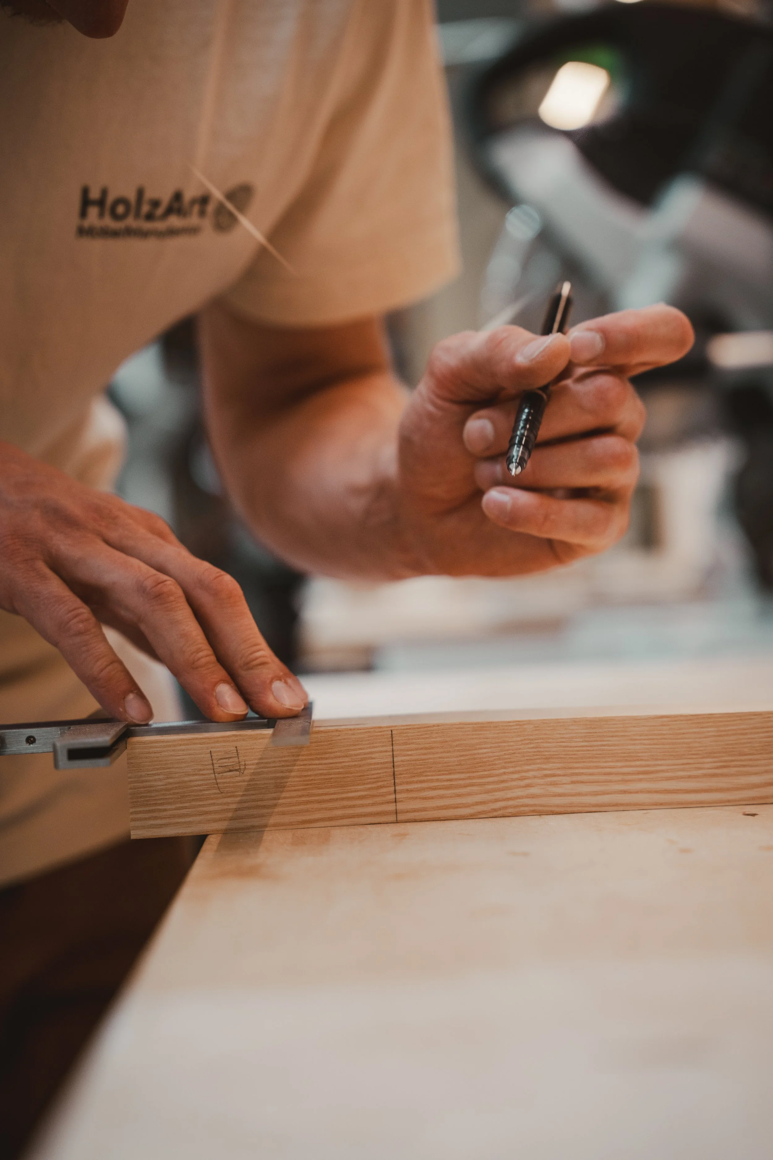 Ein Handwerker zeichnet Markierungen auf ein Stück Holz, während er es auf einem Arbeitstisch hält.