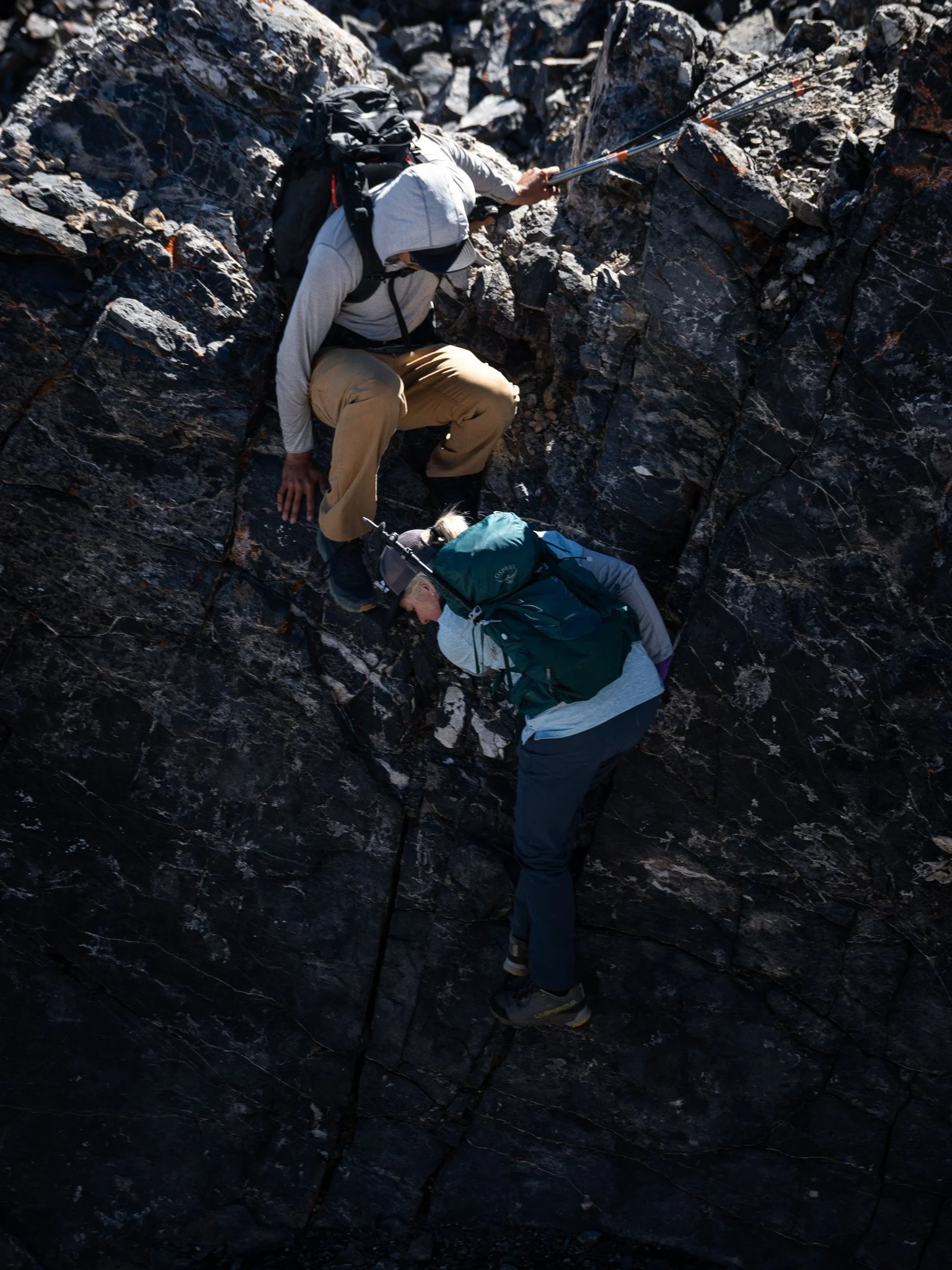 Climbers descending a steep cliff during mid-day sun.