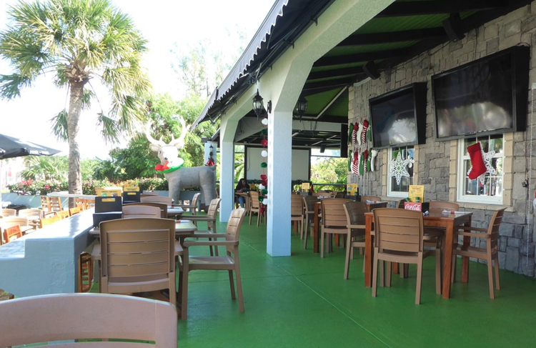 Outdoor patio area decorated for Christmas with a large reindeer figure, stockings, and holiday ornaments.