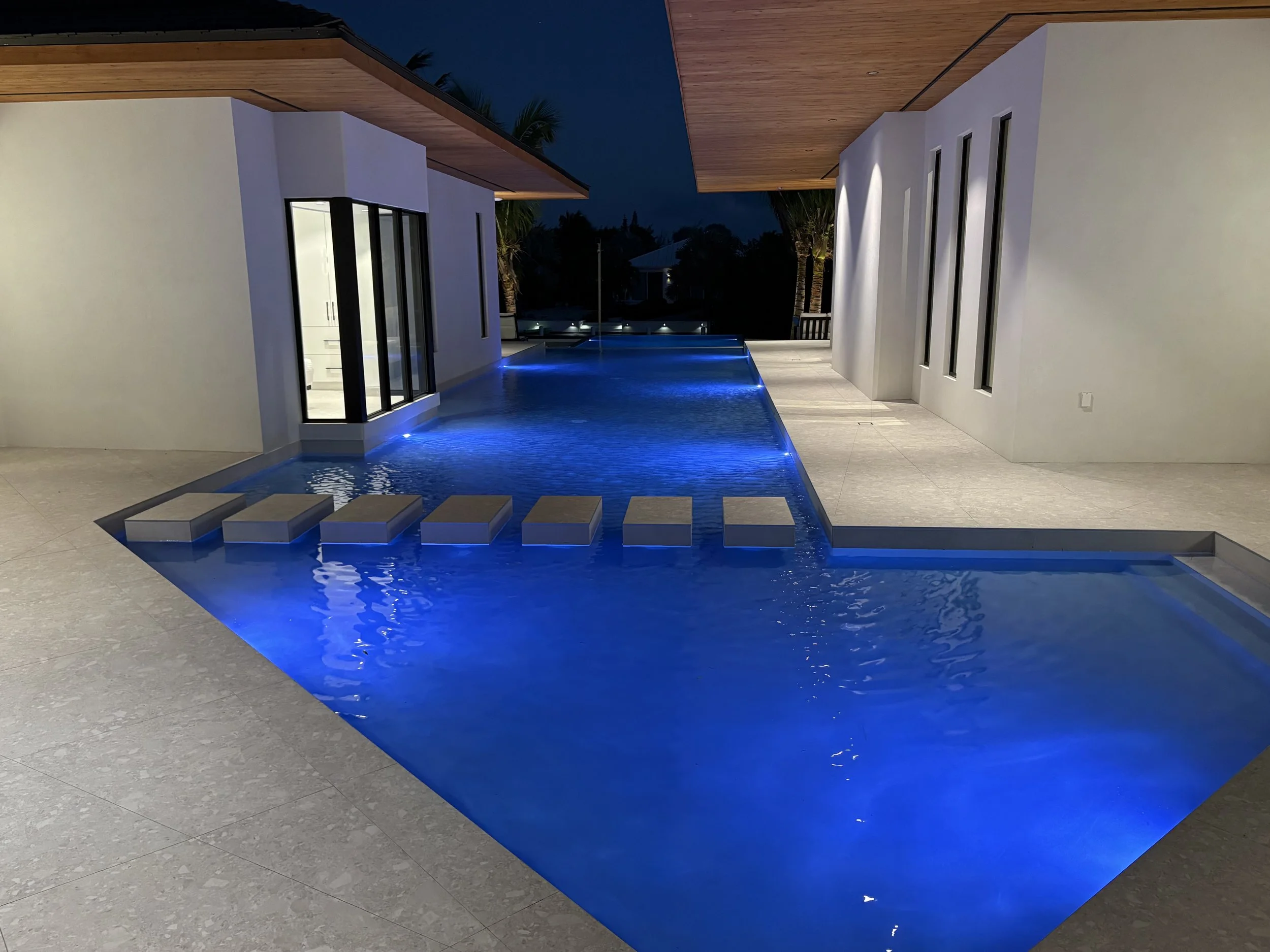 Modern house with an illuminated swimming pool and stepping stones at night.