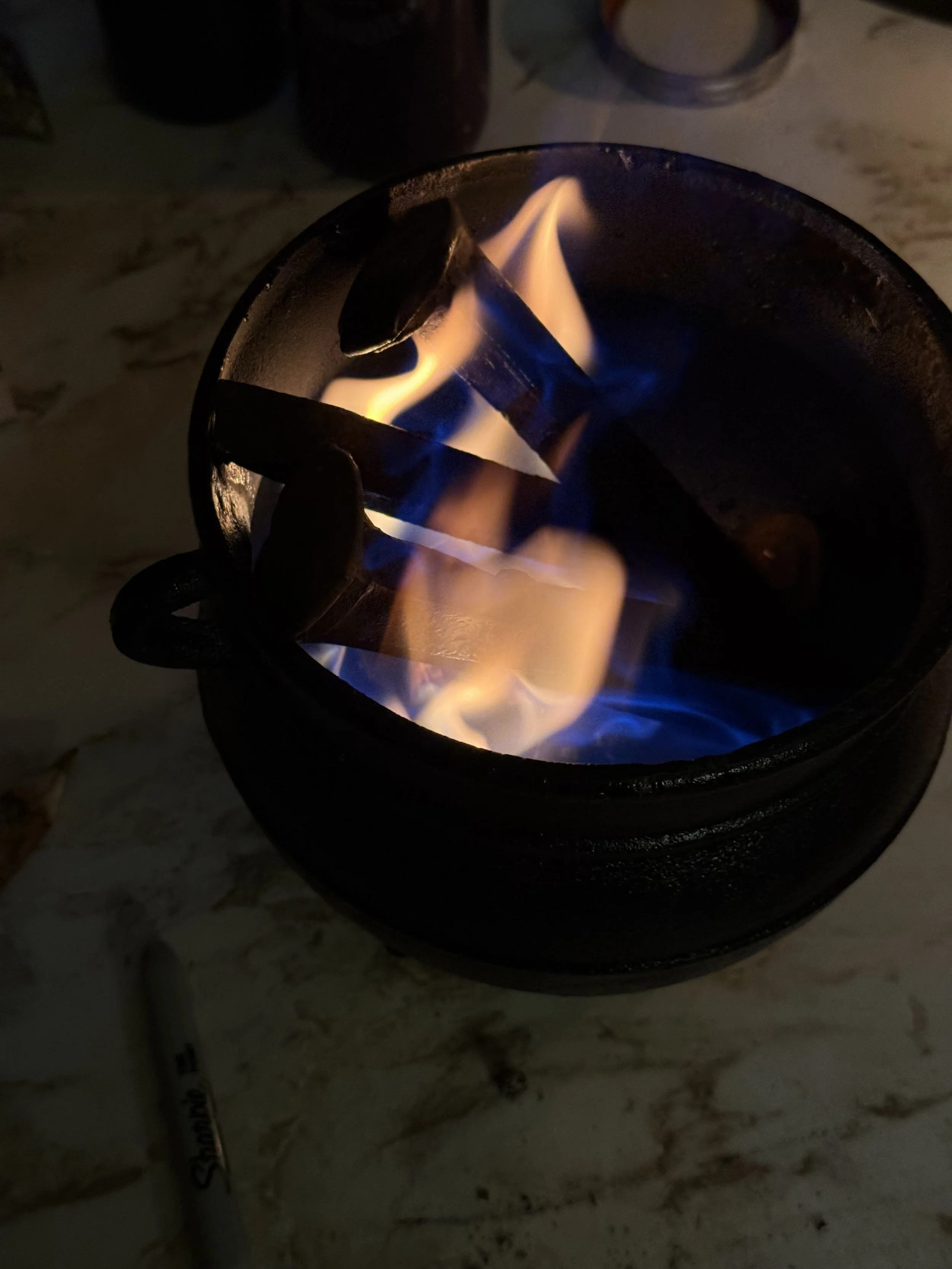 A portable stove with blue and orange flames burning inside, heating metal objects.