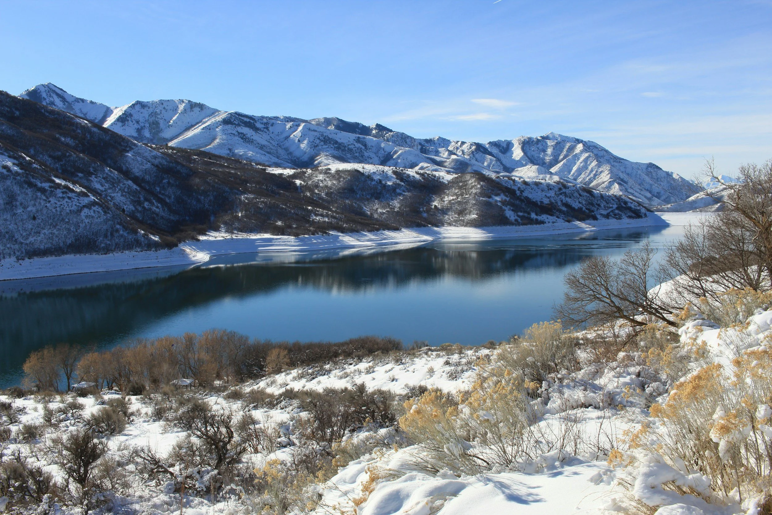 Snow-covered mountains and a river with a clear blue sky.