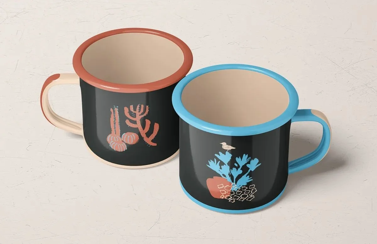 Two mugs with map icons from Lanzarote — volcanic browns, sea blues, and terracotta details.