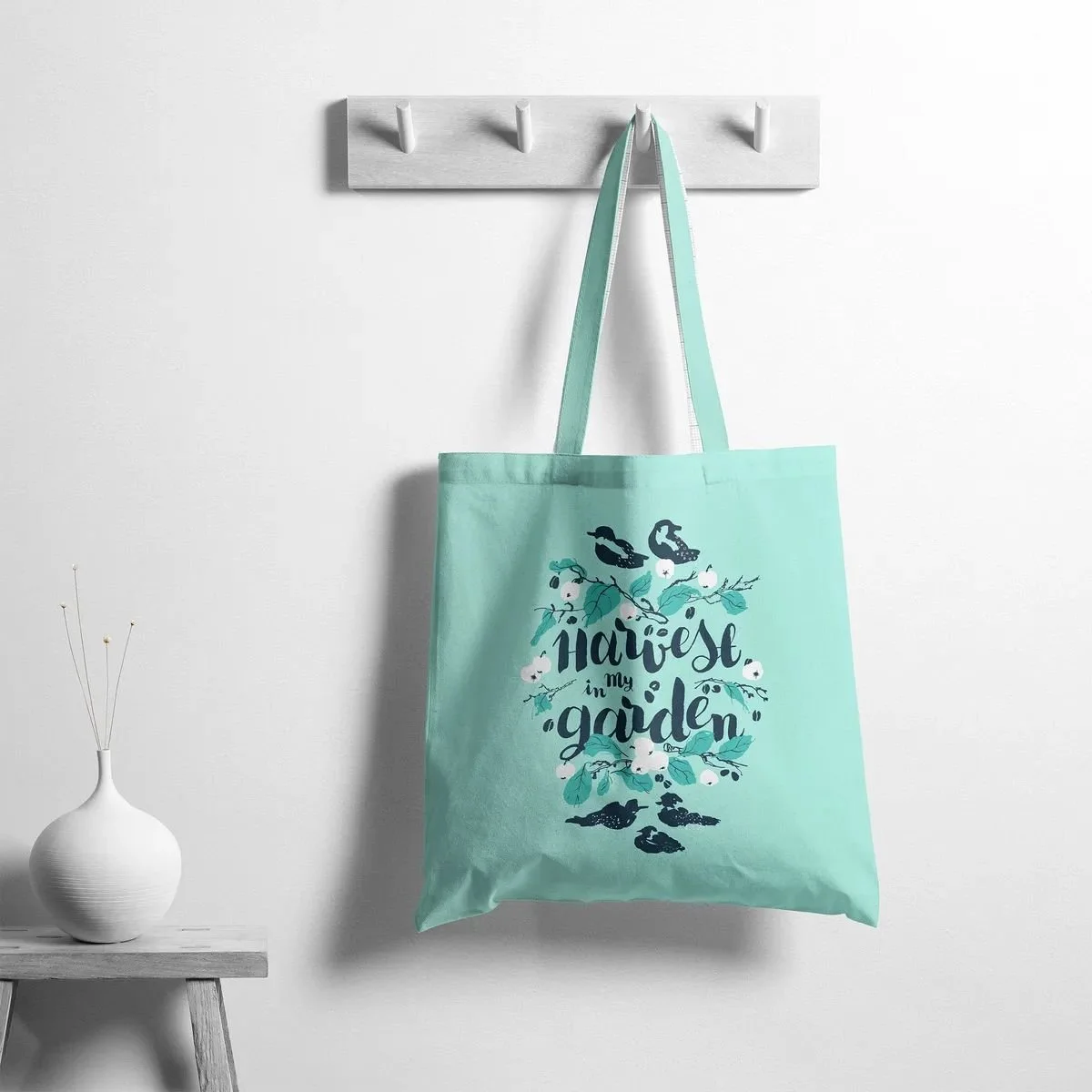 Tote bag featuring the “Harvest in My Garden” pattern — apples, plums, and birds in cool green and blue shades.