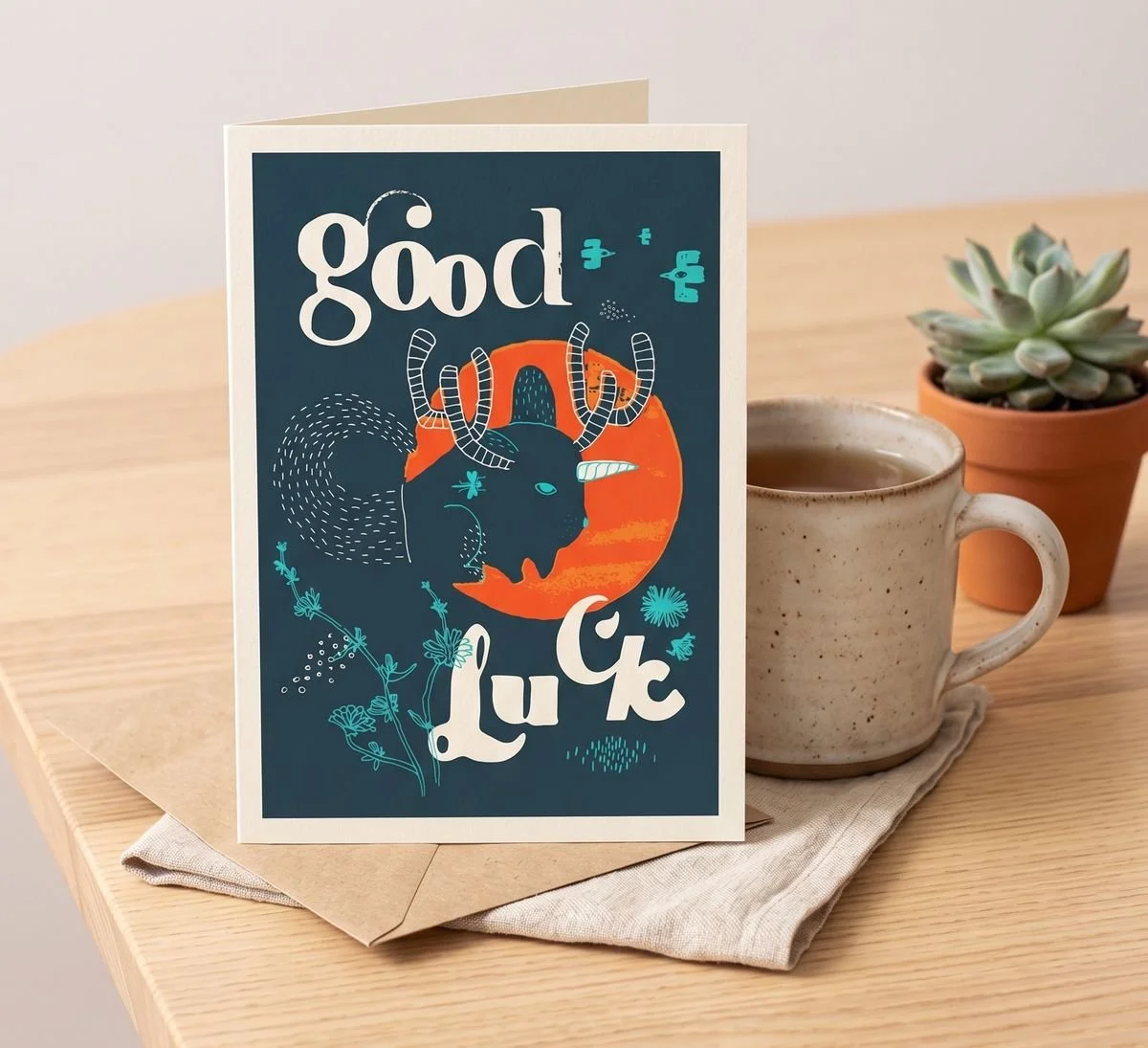 Good Luck card - flat-style indigo background with a red-orange moon and the forest spirit silhouette from the Uncanny series, turquoise floral details.