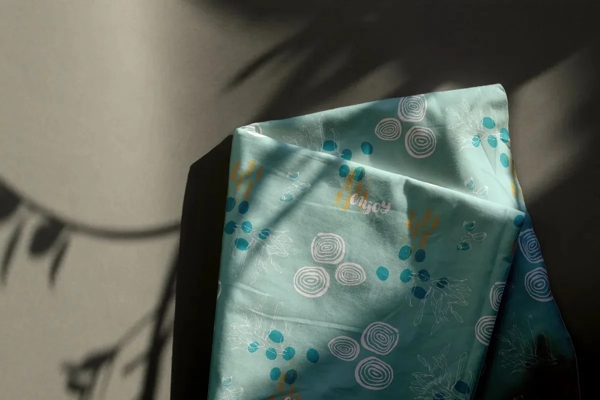 Kitchen towel featuring the “Focaccia” pattern — light turquoise background with white, dark teal, and warm yellow graphic elements.