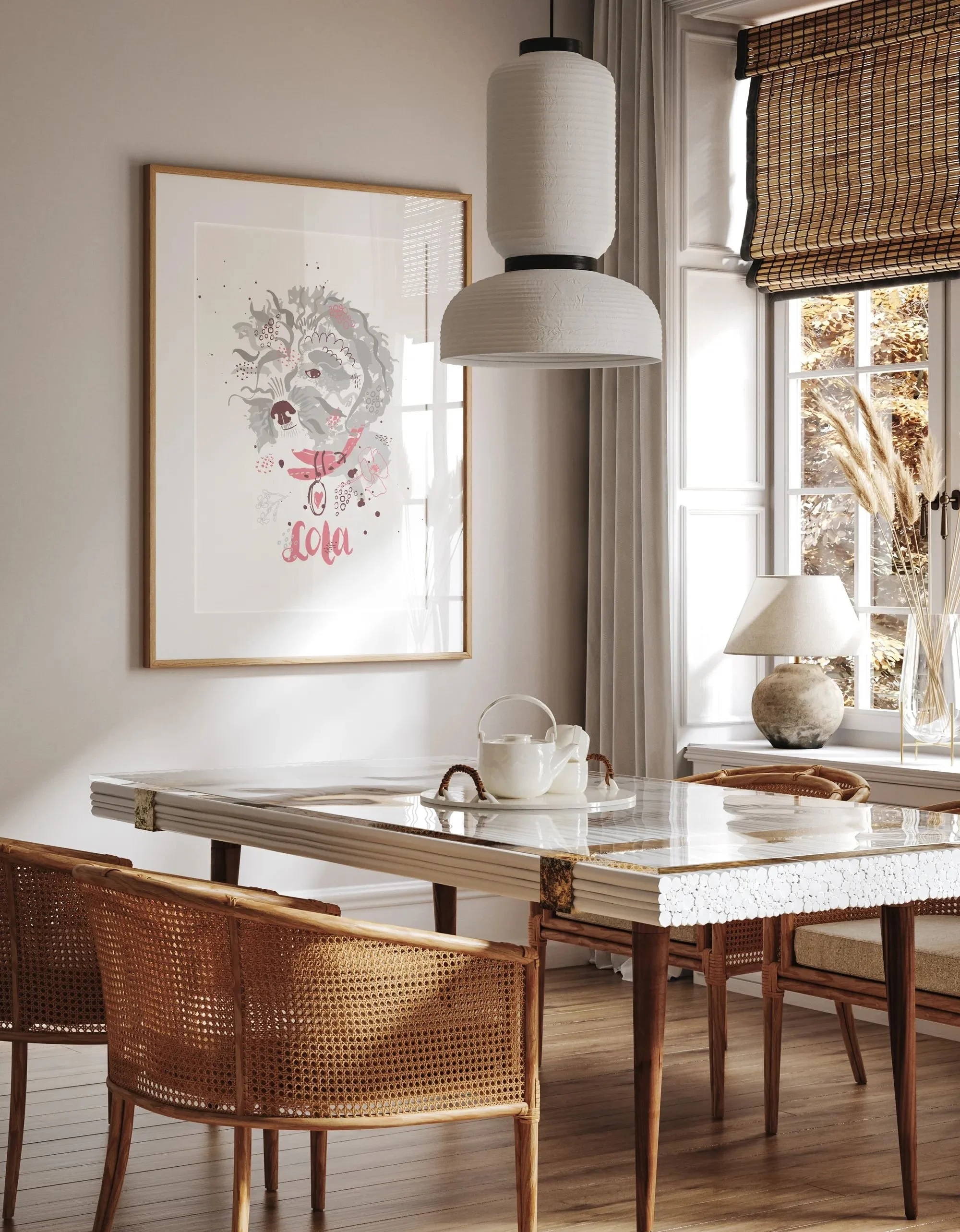 Framed portrait print of a curly-haired dog rendered in a graphic collage style, gray tones with dusty pink accents and a heart-shaped pendant on its collar, hanging in a dining room with rattan chairs and a paper pendant lamp.