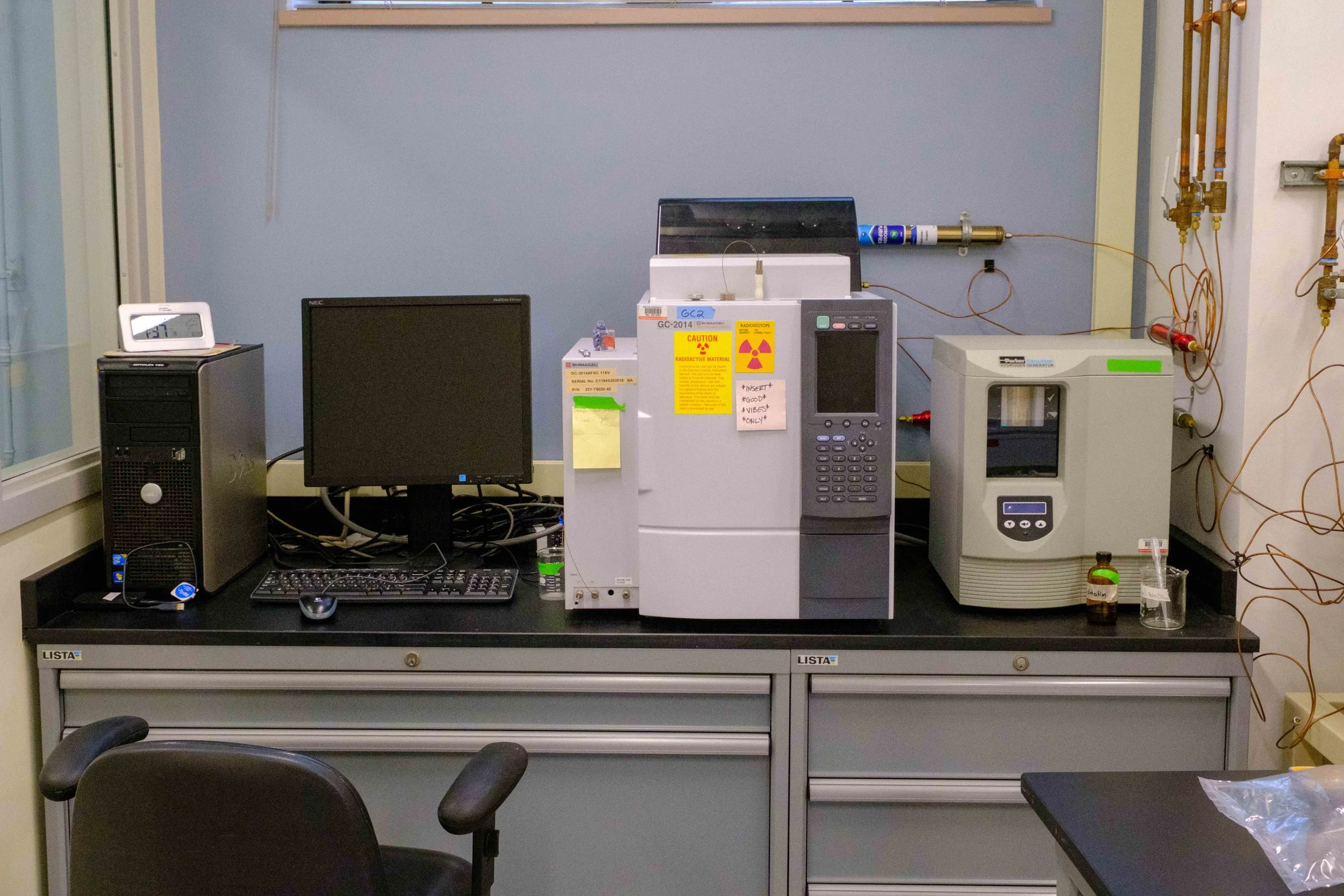 Laboratory workbench with computer, scientific instruments, and laboratory equipment including a centrifuge and a printer.