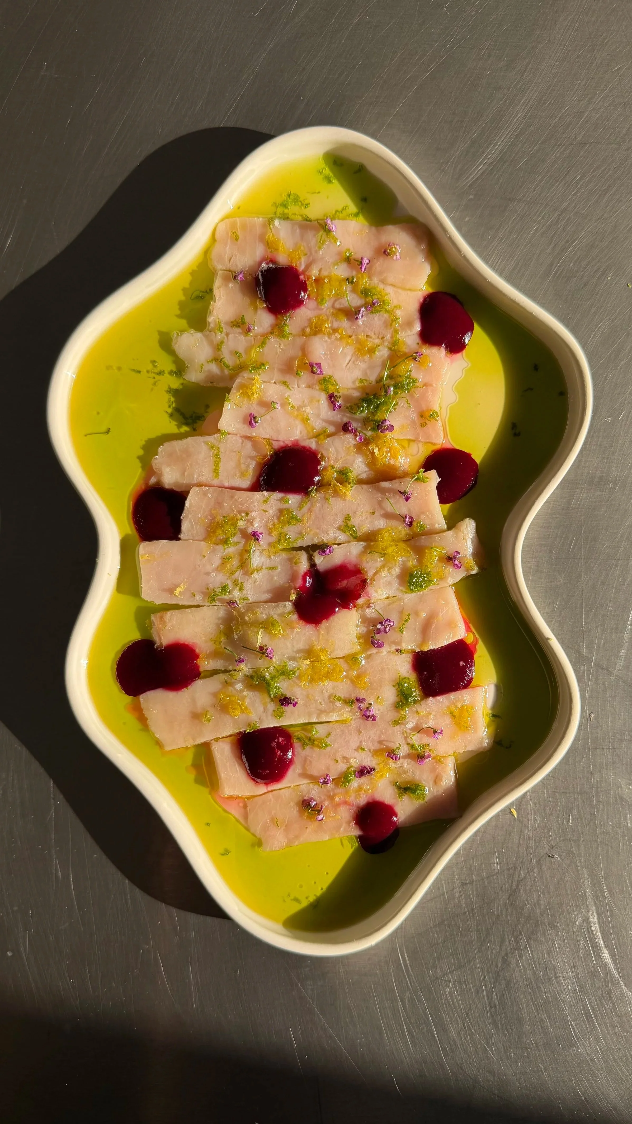 Tranches de poisson blanc, garnies d'un ketchup de cassis, huile de feuilles de figuier dans une assiette en forme de nuage