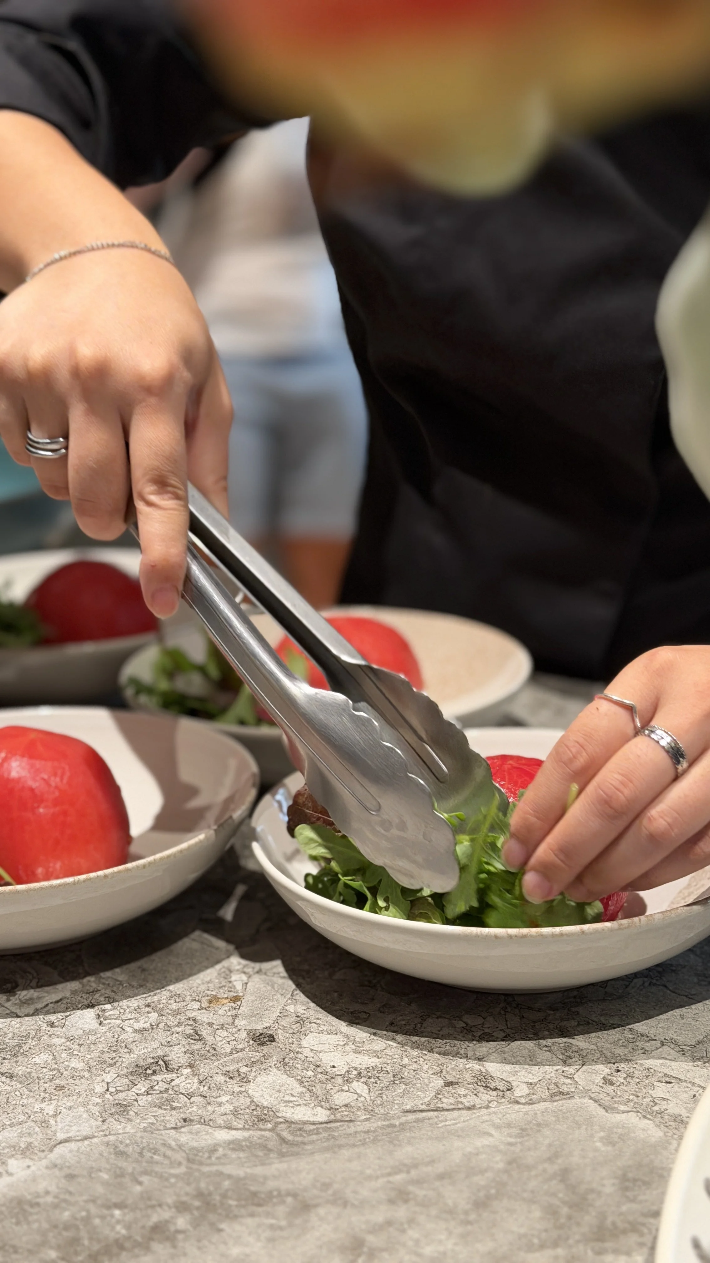 Une personne en train de servir une salade dans une assiette lors d'un dîner privé pour un evjf