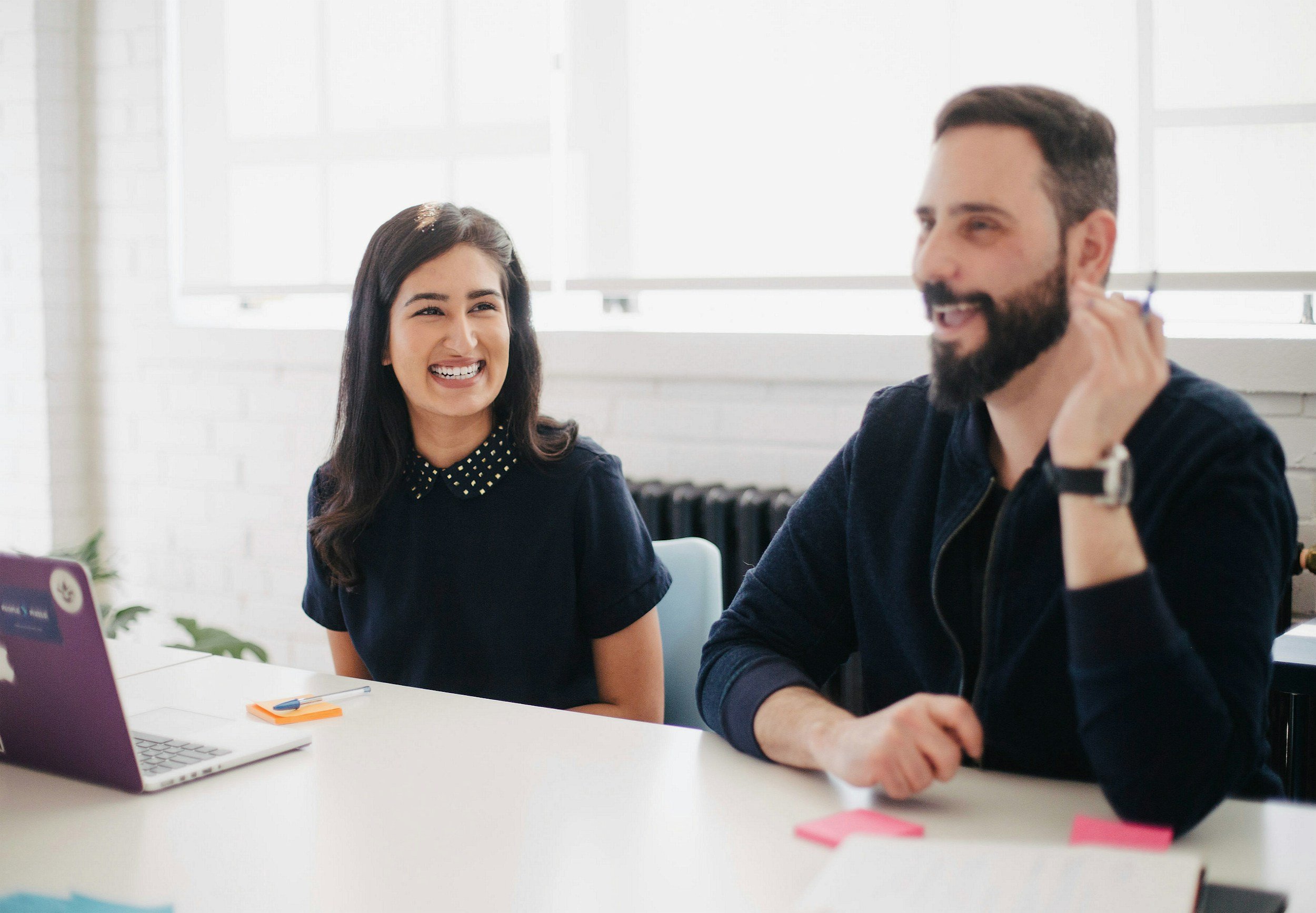 Man and woman sitting in office conference room smiling