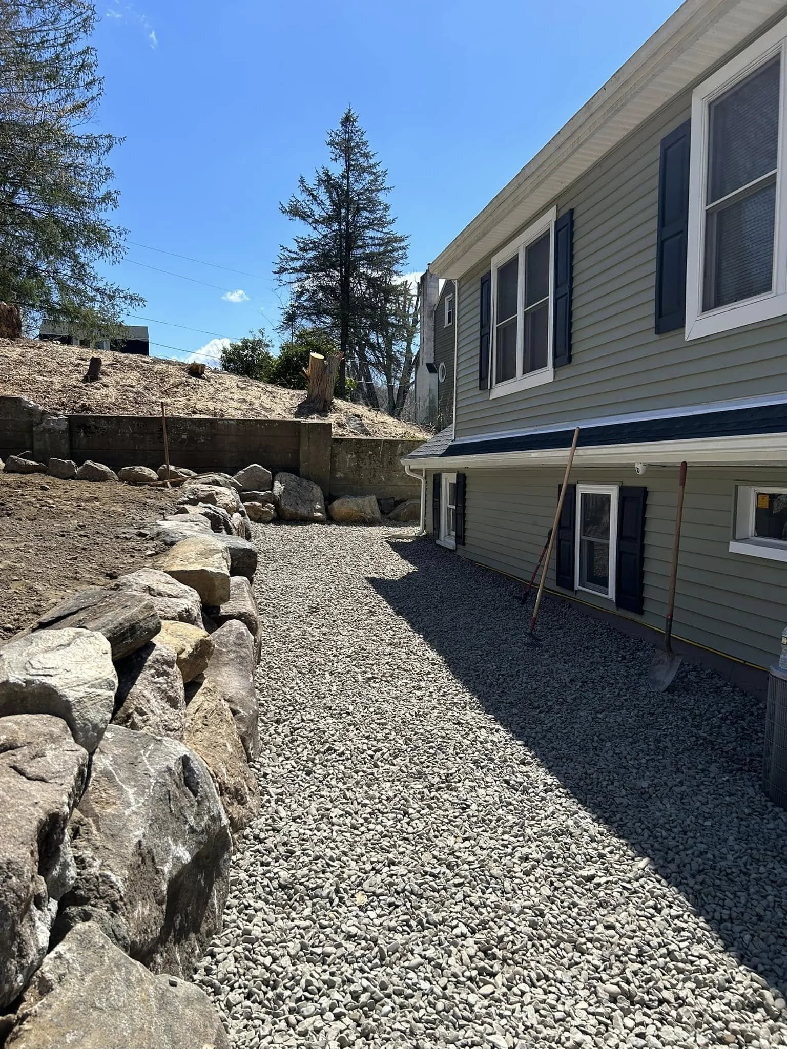 Backyard with gravel pathway and  stone border wall.