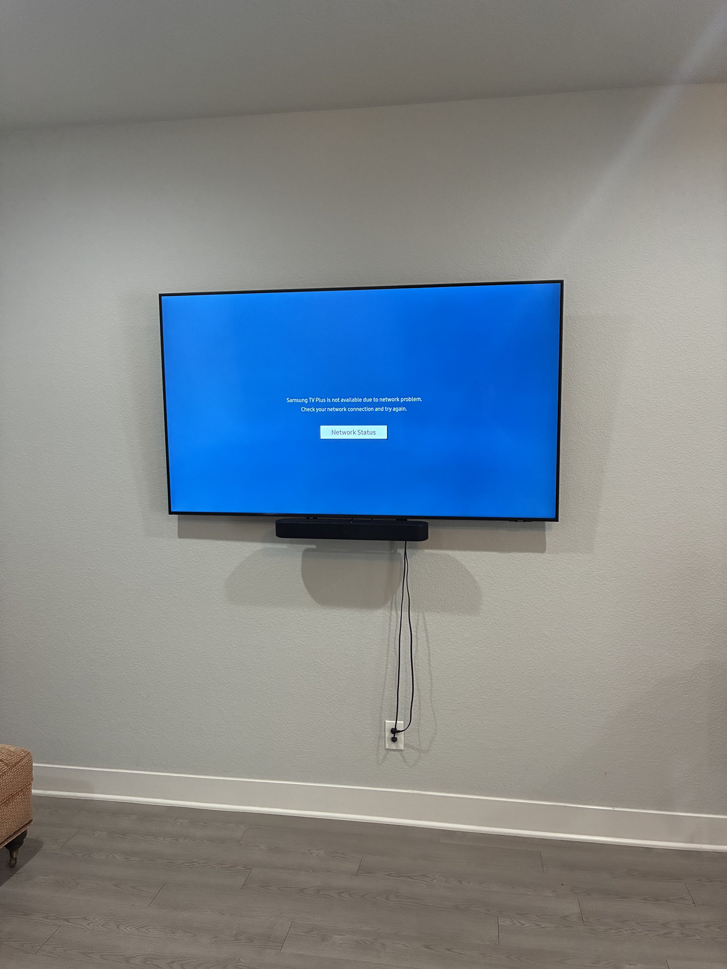 A flat-screen television mounted on a wall displays a blue error screen indicating network problems, with a button labeled 'Network Status' below.