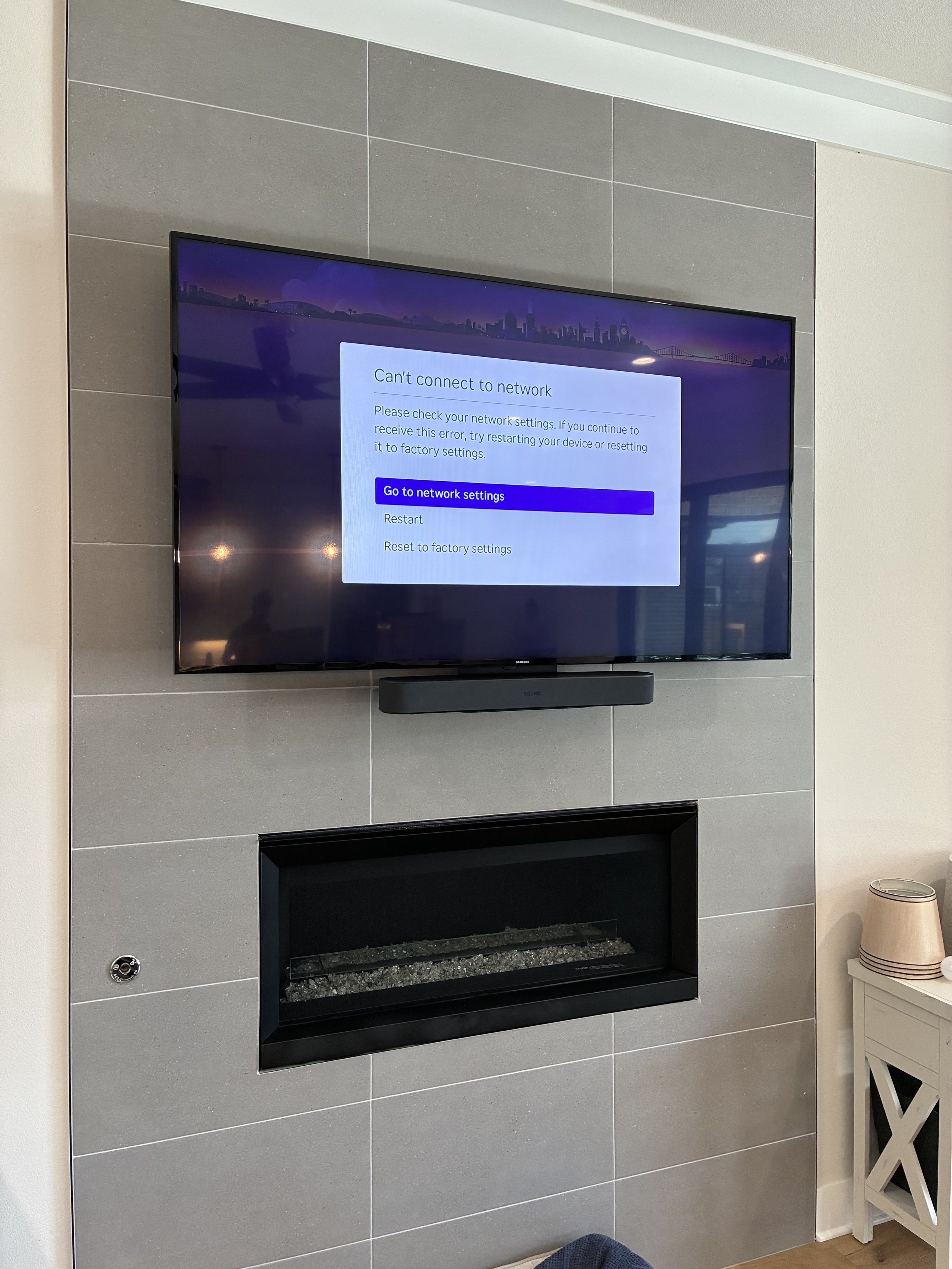 TV displaying a network connection error message on a gray tiled wall.