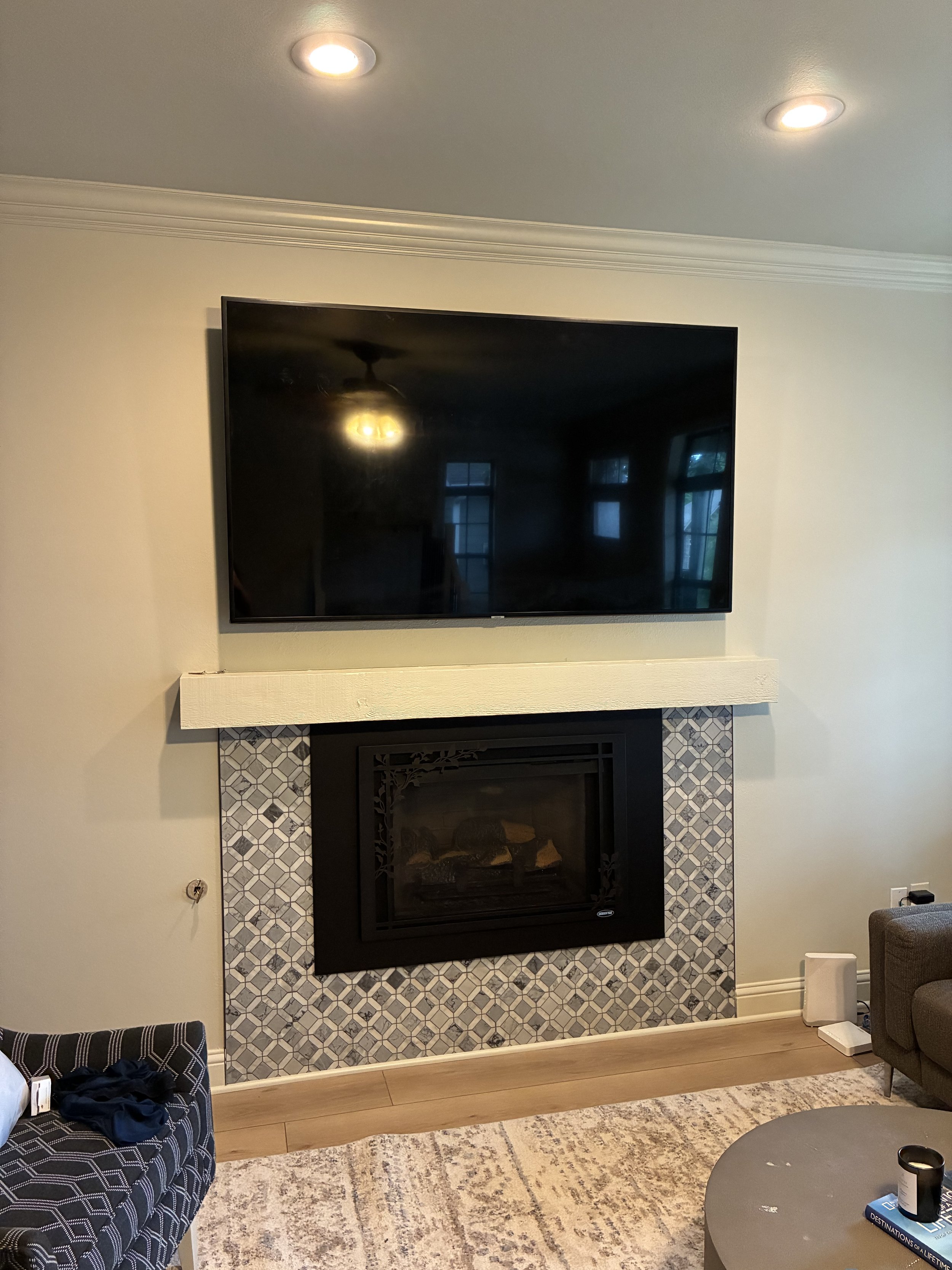 Flat-screen television mounted above a decorative fireplace with patterned tiles in a living room.