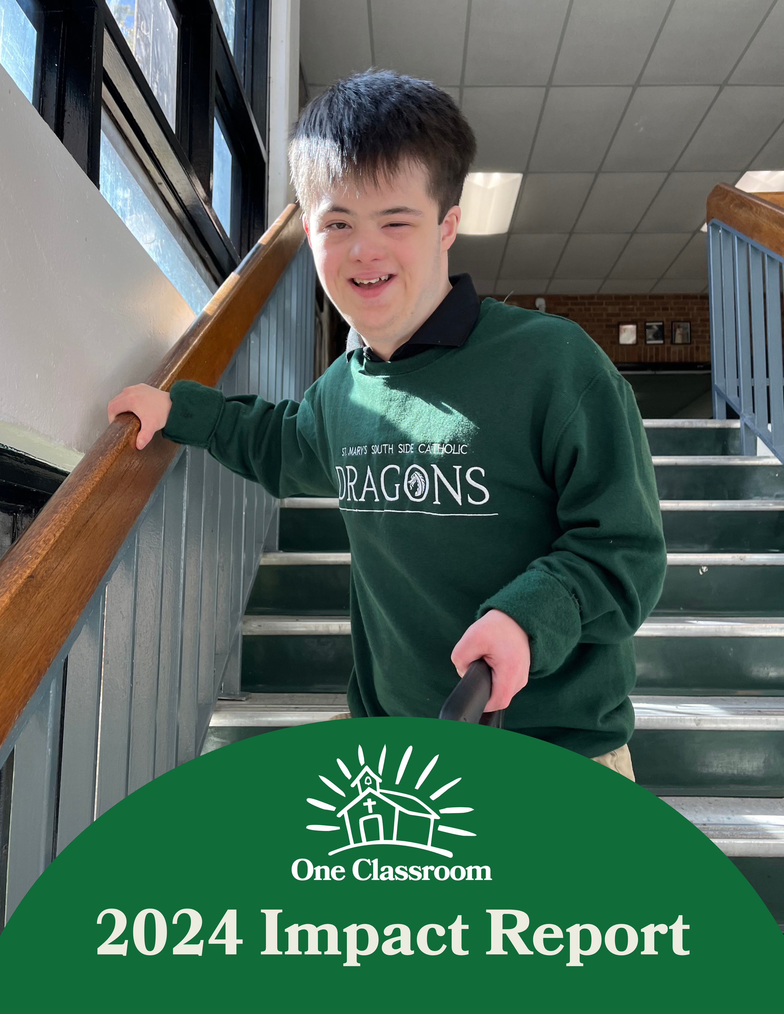A young man with dark hair, wearing a black collar and green sweatshirt with 'St. Mary's South Side Catholic Dragons,' stands on school stairs holding a phone, smiling in sunlight.