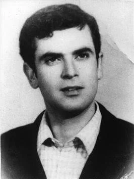 Black-and-white portrait of a young man with dark hair, wearing a collared shirt and jacket.