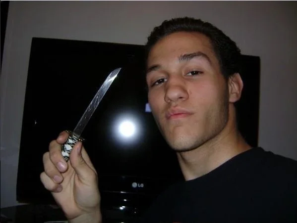 Young man holding a knife in front of a TV screen
