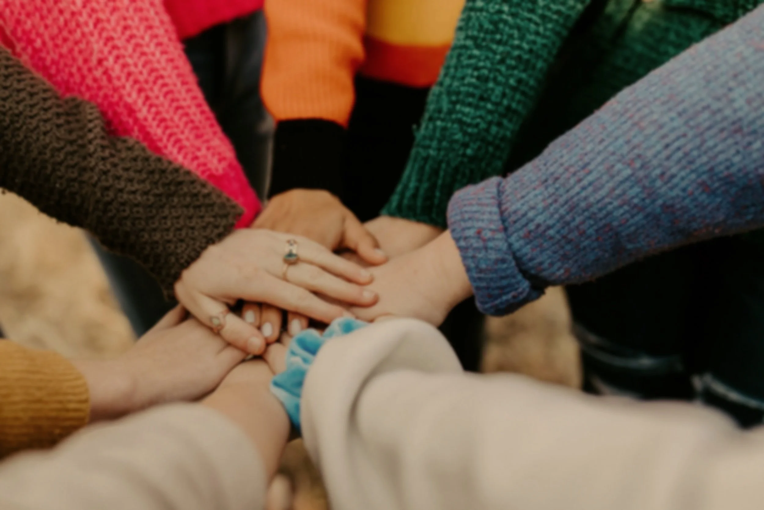 A group of people standing in a circle, with their hands placed on top of one another