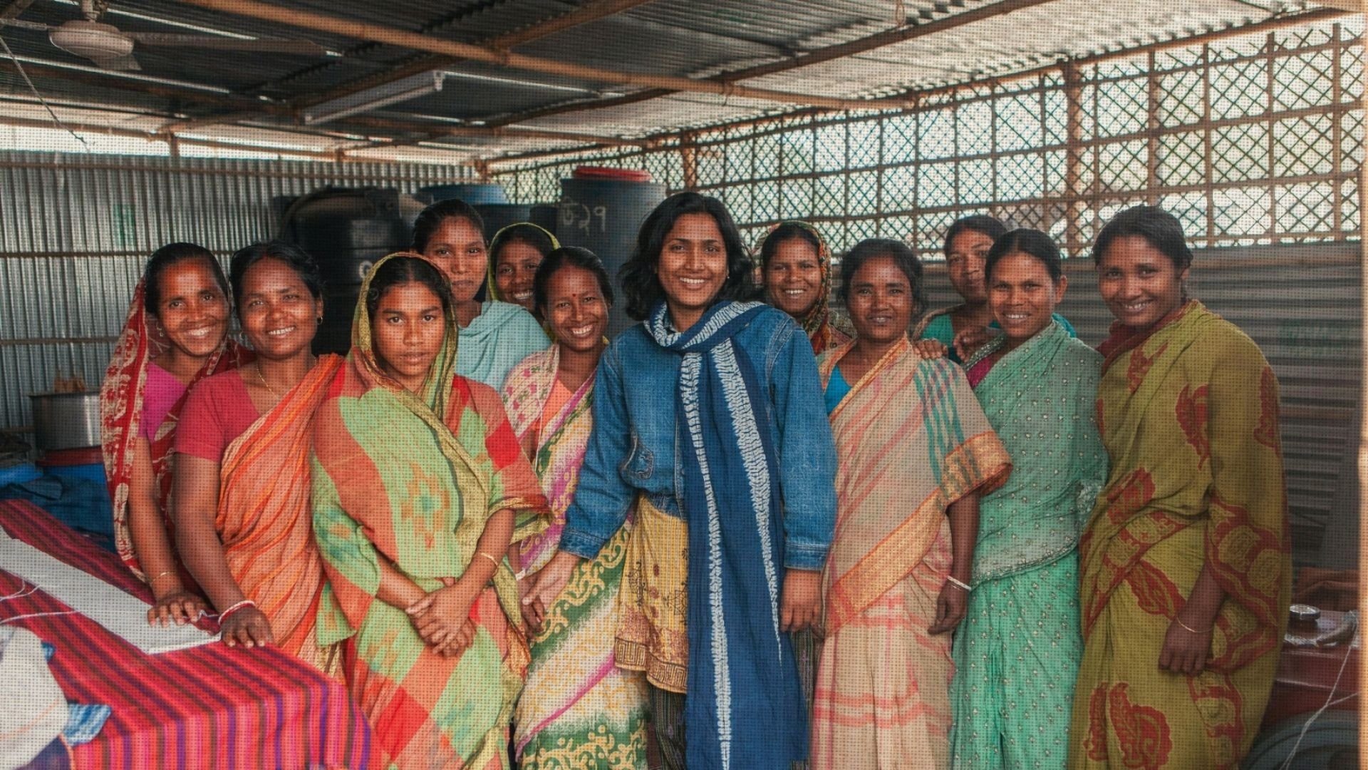 A group of women standing together in a village community centre, smiling