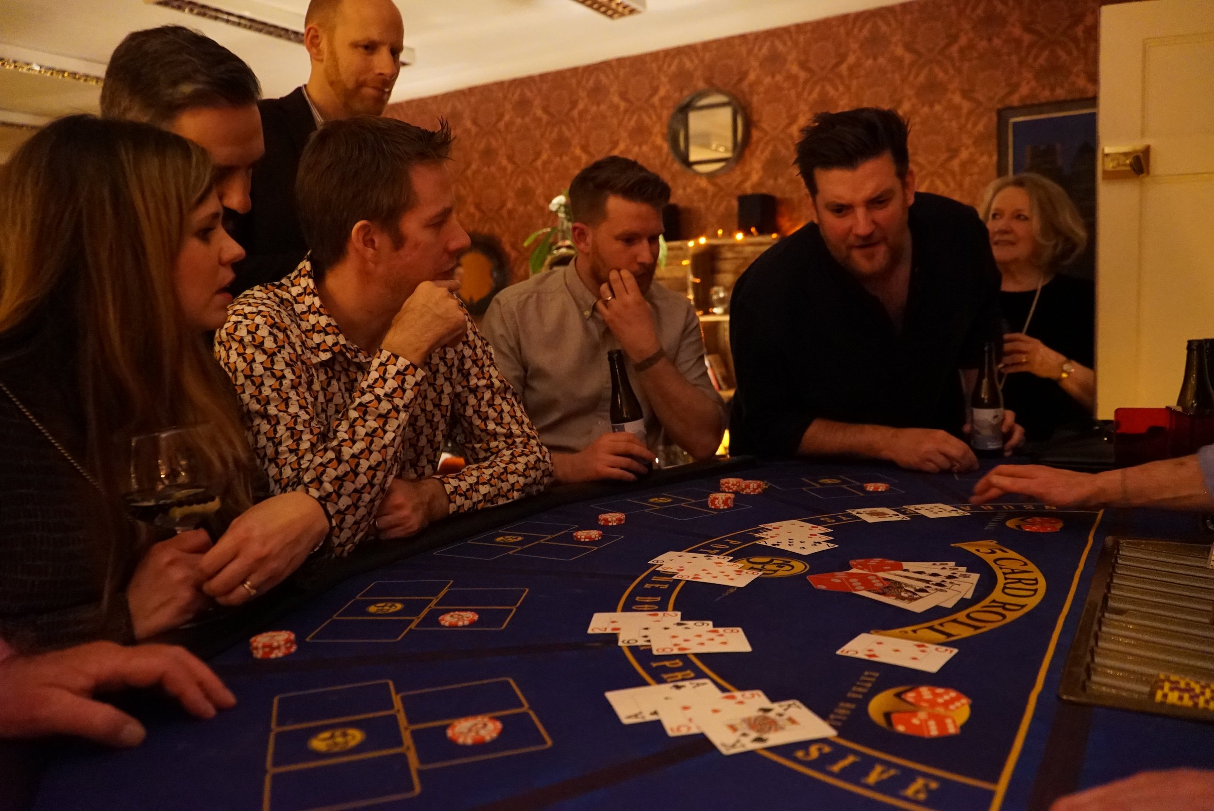 People gathered around a casino blackjack table playing a card game.