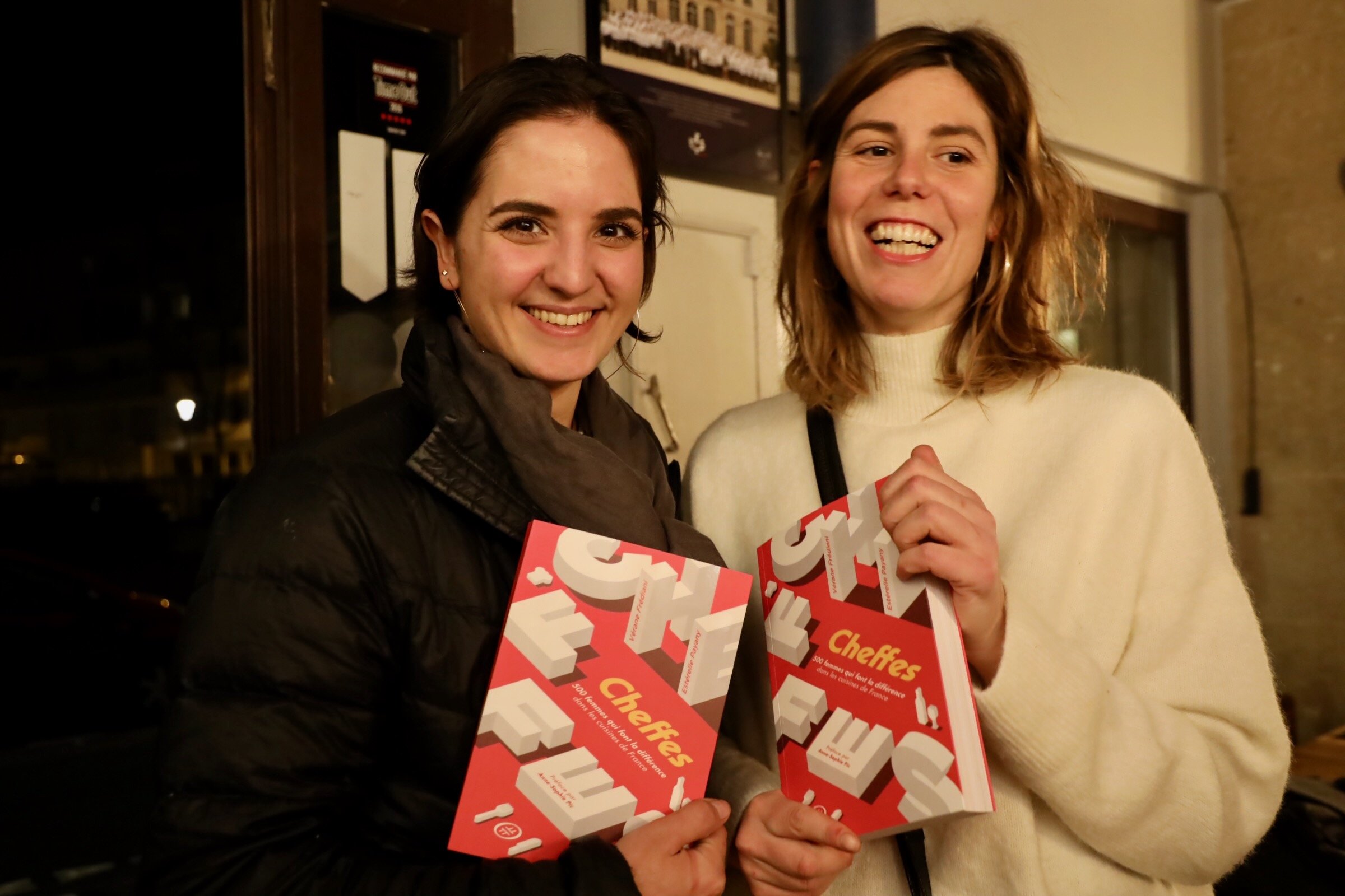 Two female chefs LAETITIA VISSE and MIKAELA LIAROUTSOS , smiling and holding Cheffes, the database written by Vérane Frediani and Estérelle Payany.