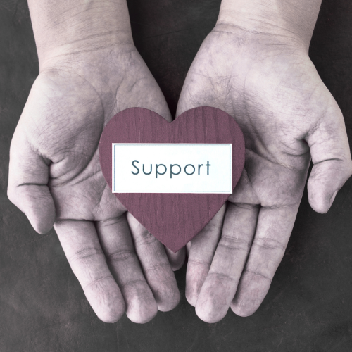 Two hands holding a wooden heart with the word 'Support' on it.